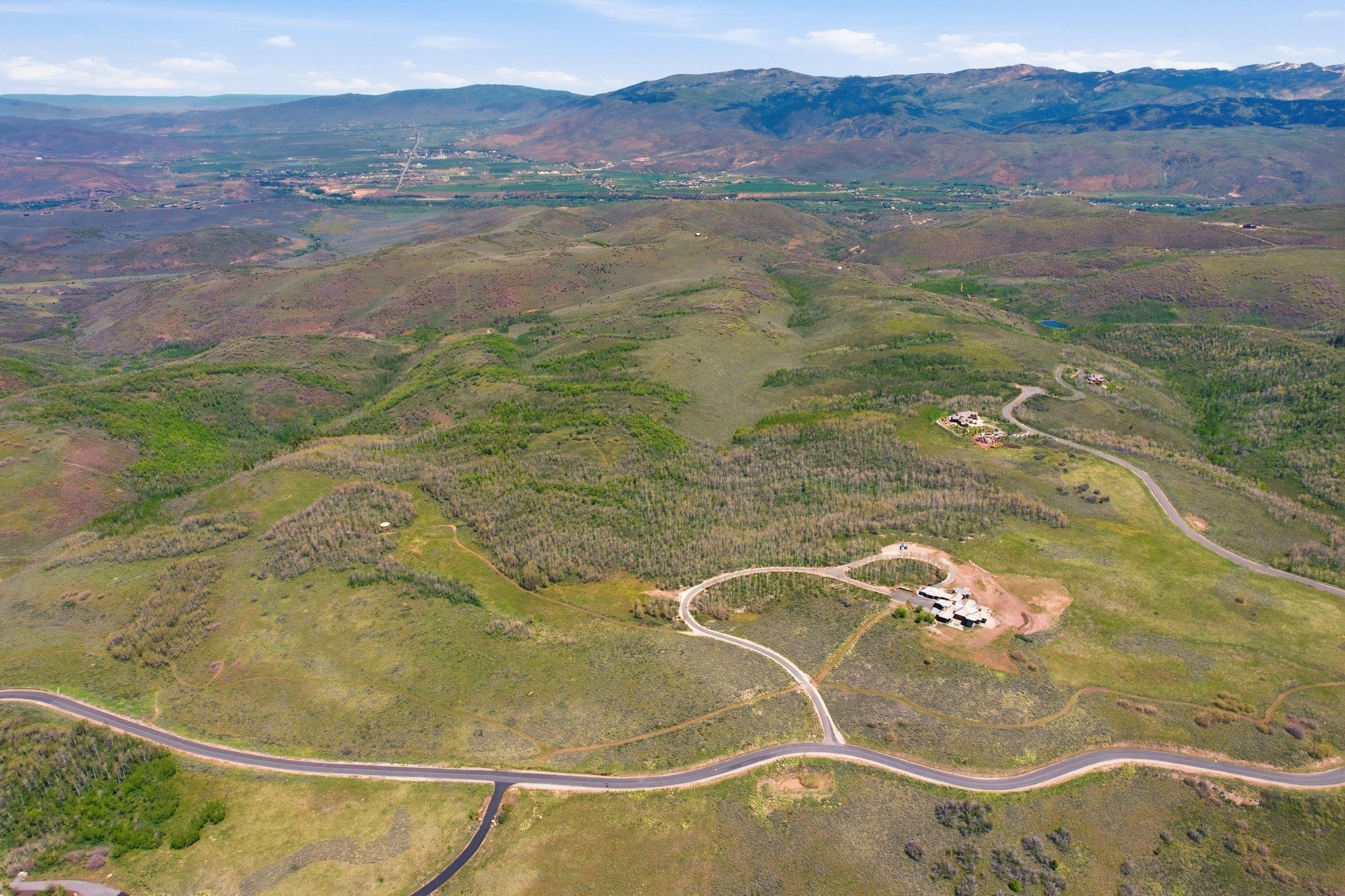 Expansive mountain landscape featuring varied terrain and distant housing structures