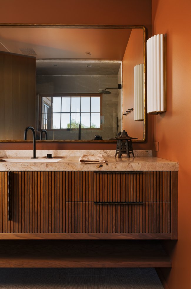 Vanity featuring a fluted wood-finish base with integrated drawers, a stone countertop, and a vessel sink with a wall-mounted faucet