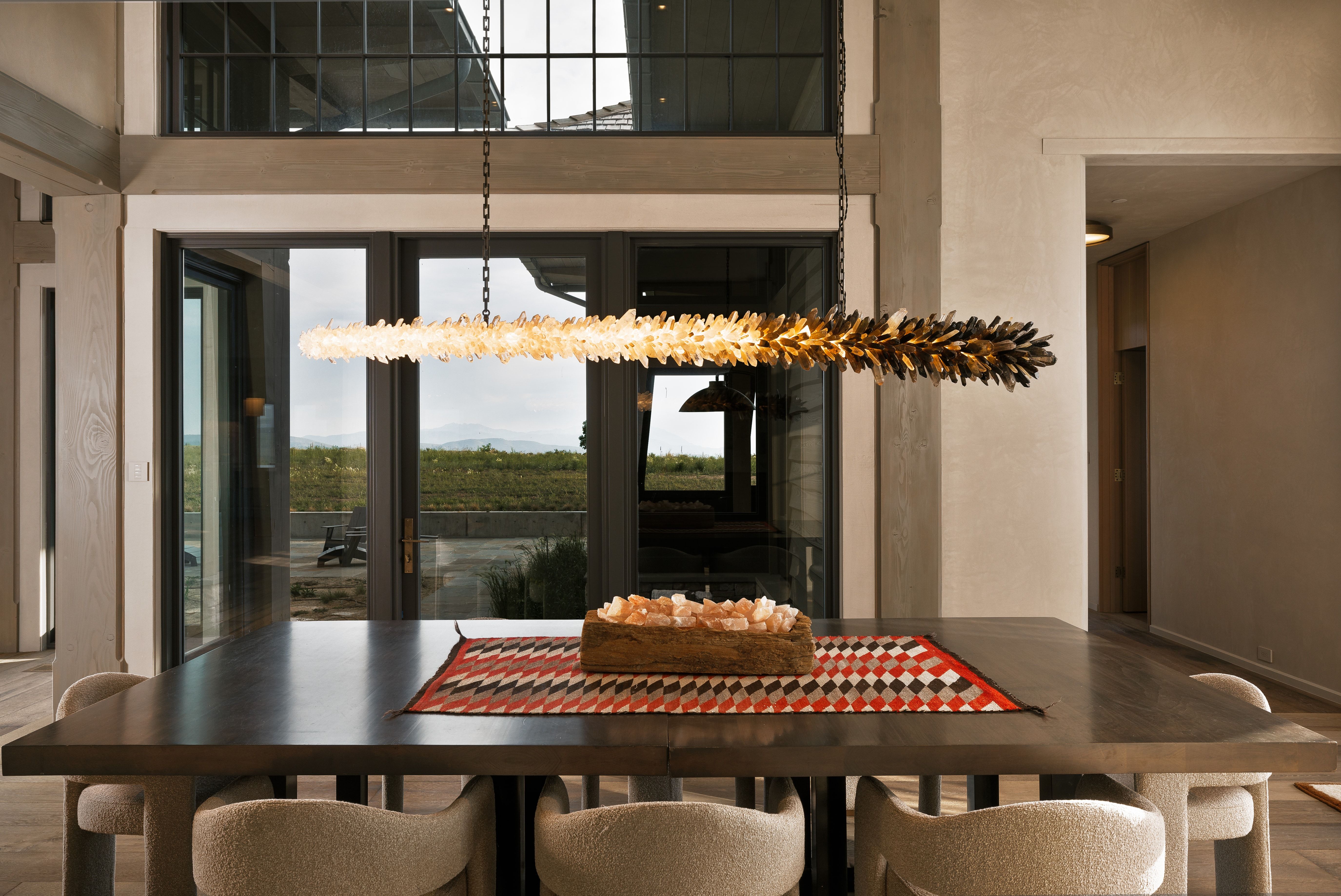 Dining area featuring a linear chandelier with a dual-tone finish, a dark-finish dining table, and light-toned walls