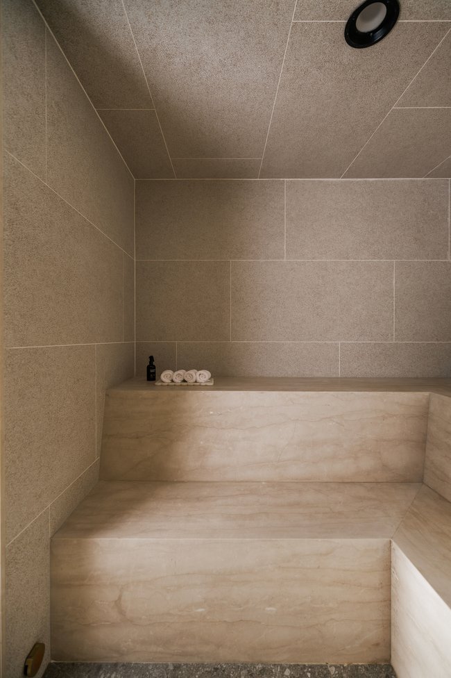 Built-in tiered stone bench seating within a tiled room, featuring a recessed ceiling light
