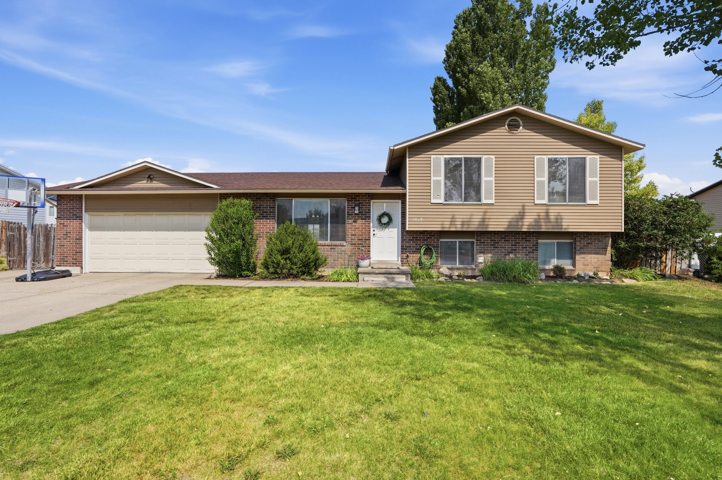 Split-level residence featuring a brick and siding exterior, an attached two-car garage, and a concrete driveway