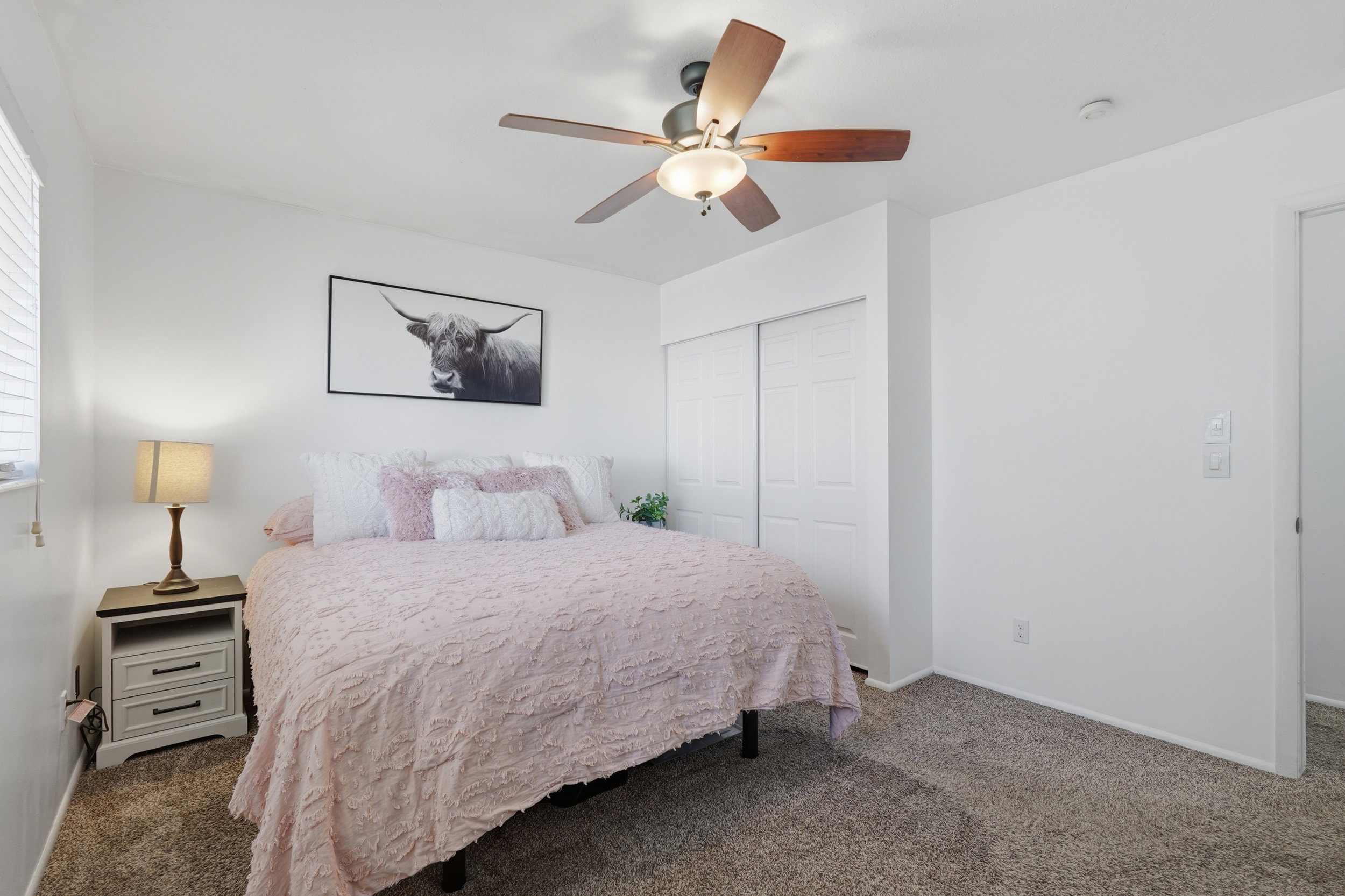 Neutral wall finishes, textured carpeting, and a ceiling fan with integrated lighting