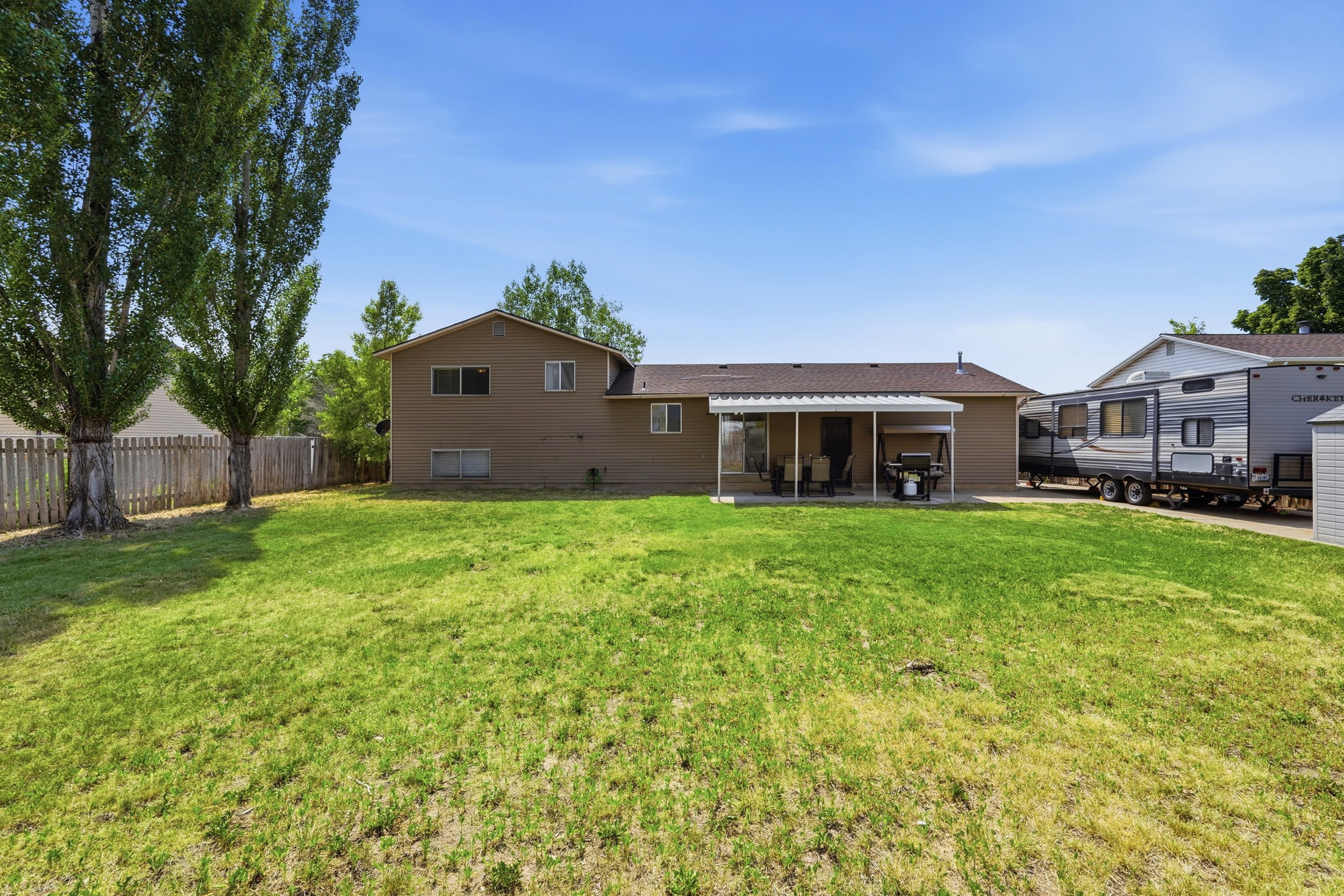 Expansive rear yard featuring green lawn and a covered patio