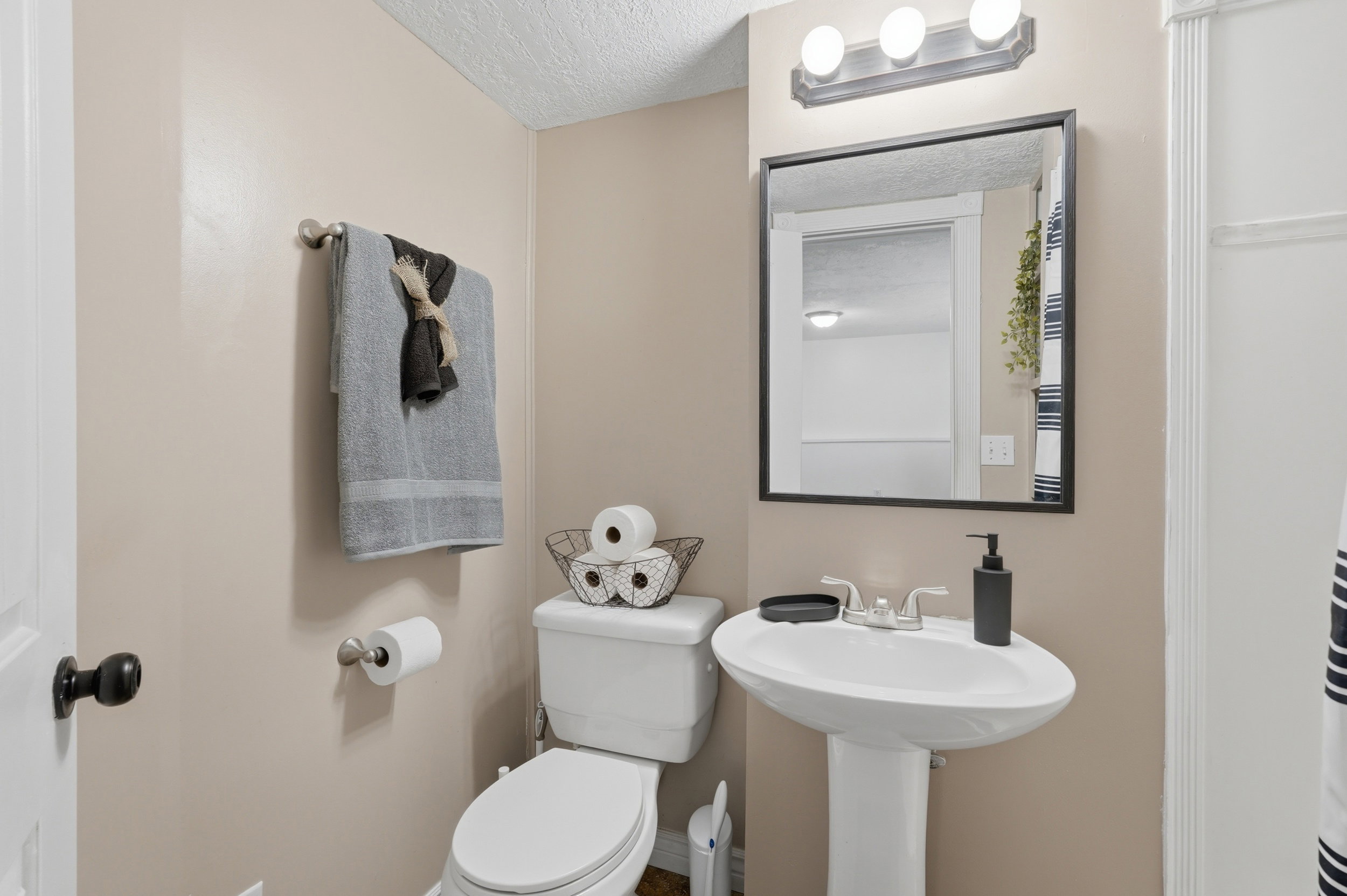 Bathroom featuring a pedestal sink with chrome faucet, a rectangular framed mirror, and a three-light vanity fixture