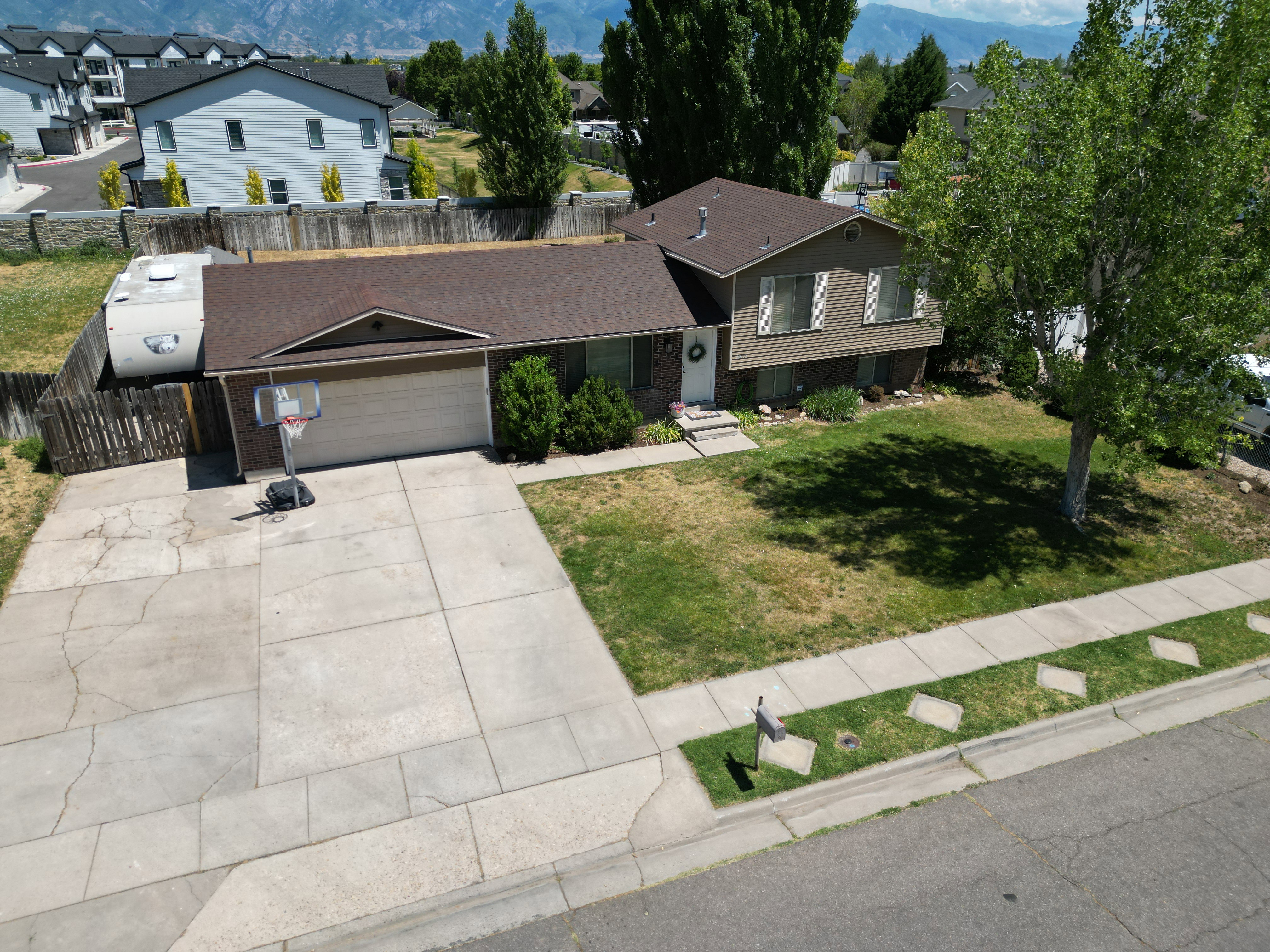 Split-level residence featuring a two-car garage, concrete driveway, and established front yard