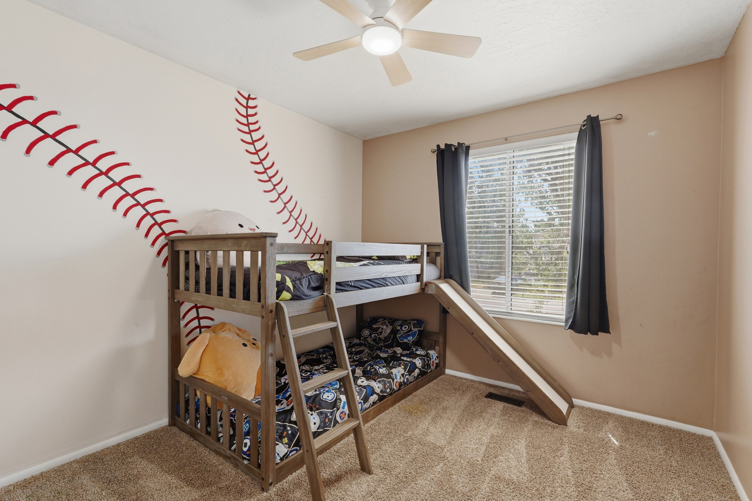 Carpeted room featuring a ceiling fan with integrated lighting, a window with blinds and dark curtains, and light-colored walls