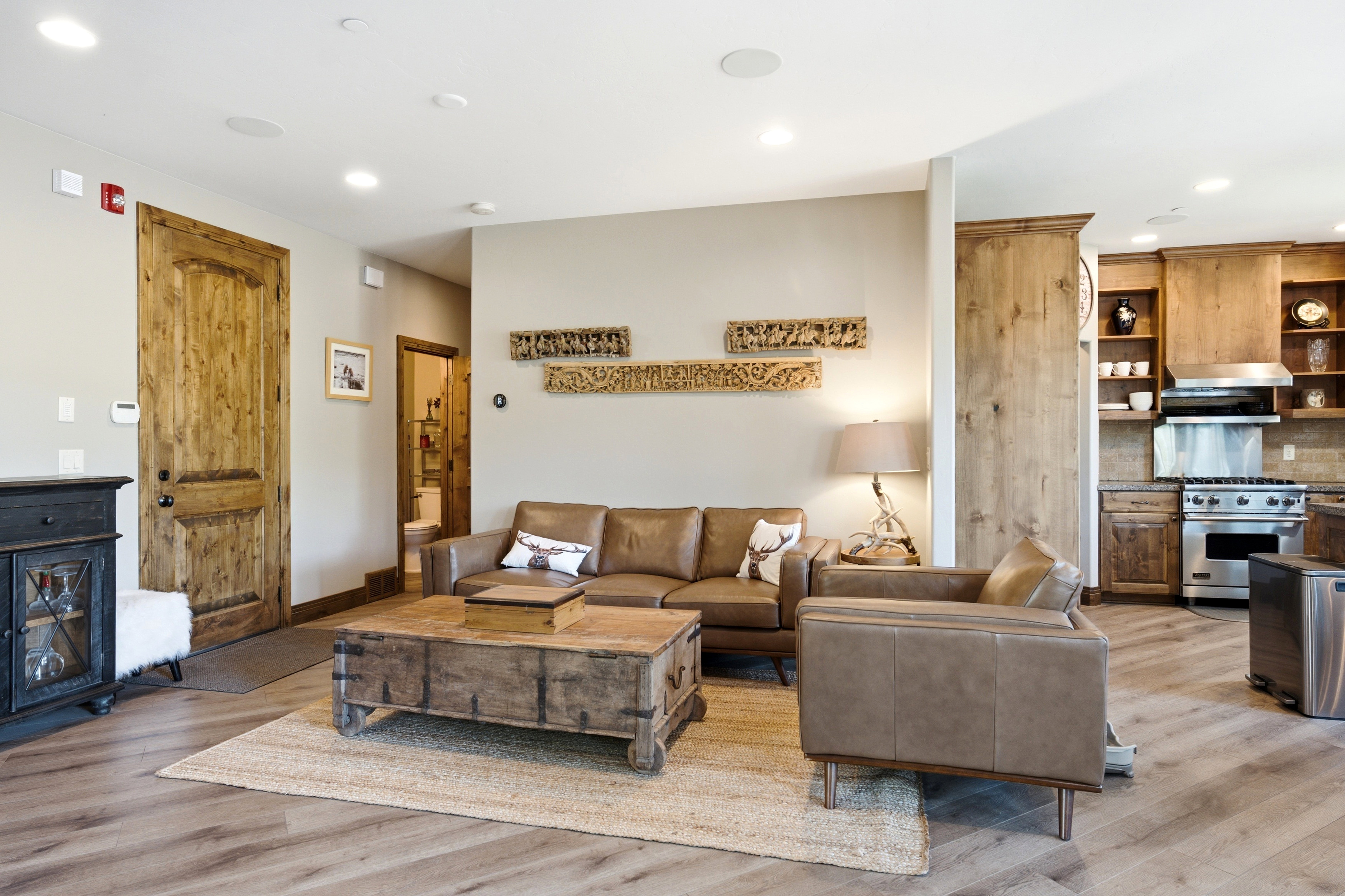 Open-concept living area featuring wood-finish flooring, recessed lighting, and a handcrafted wooden door