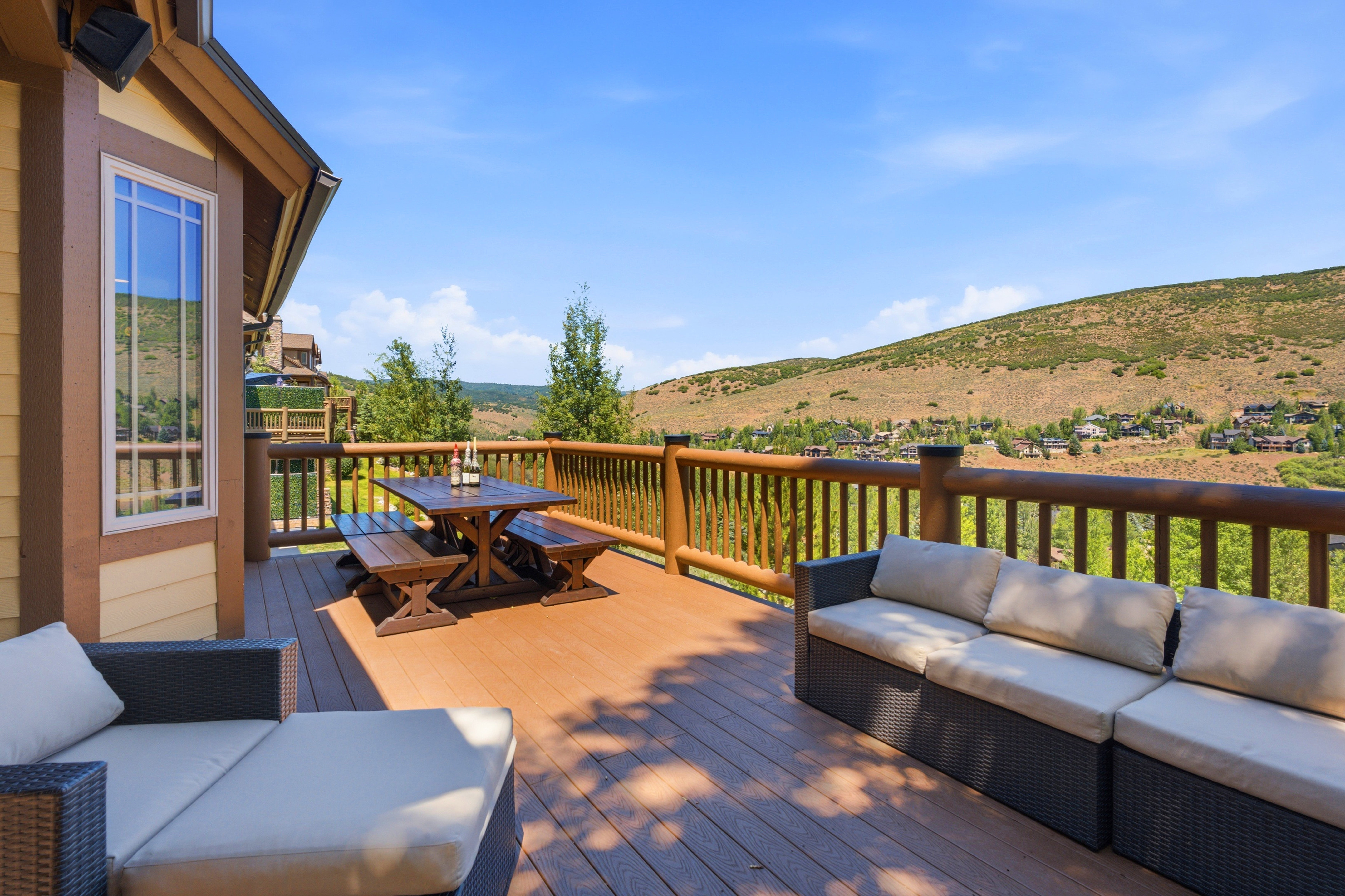 Expansive outdoor deck featuring composite decking, log railing, and a window with white trim
