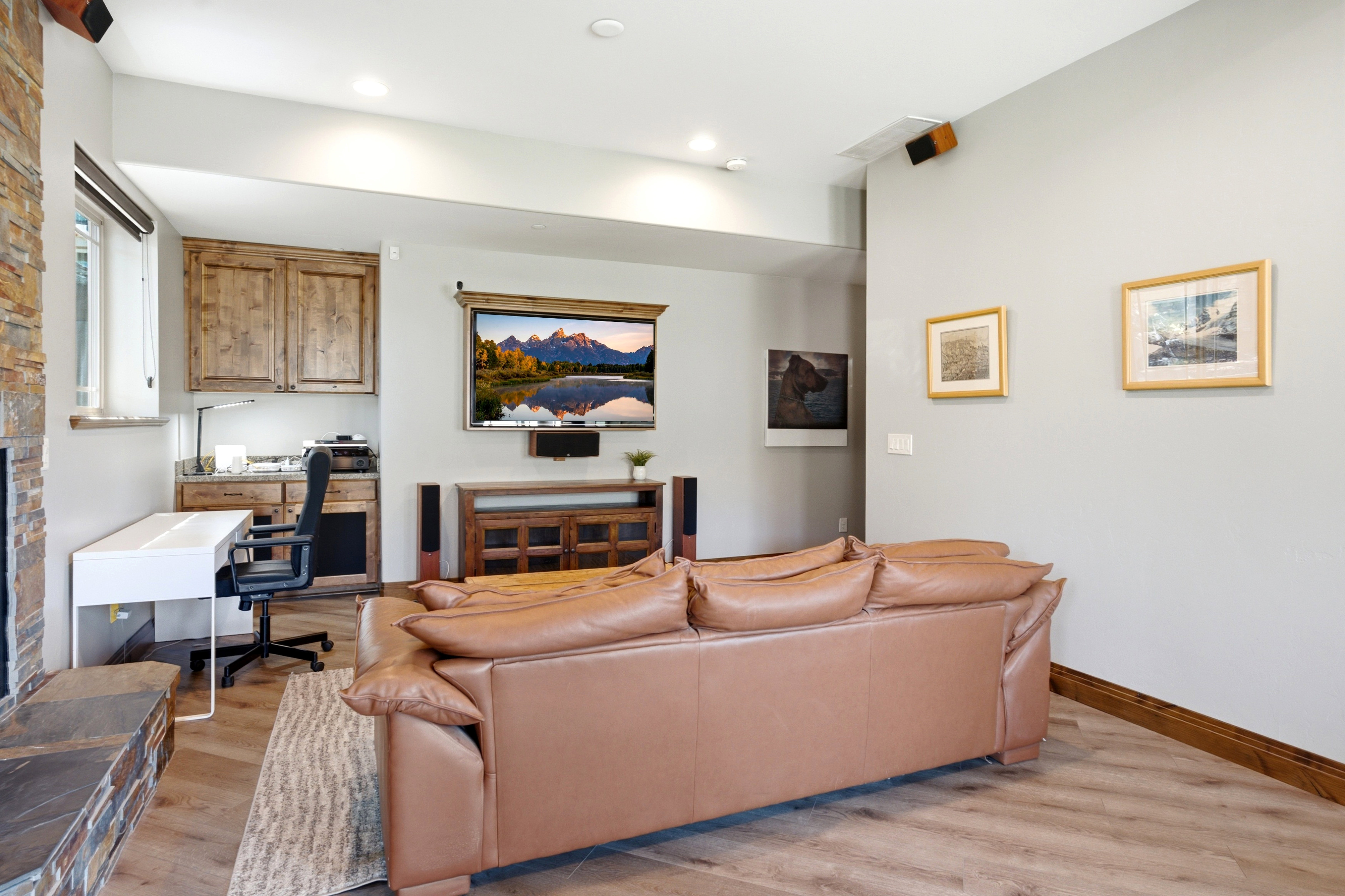 Living area featuring wood-finish flooring, a stone accent wall, recessed lighting, and a built-in workstation with wood cabinetry