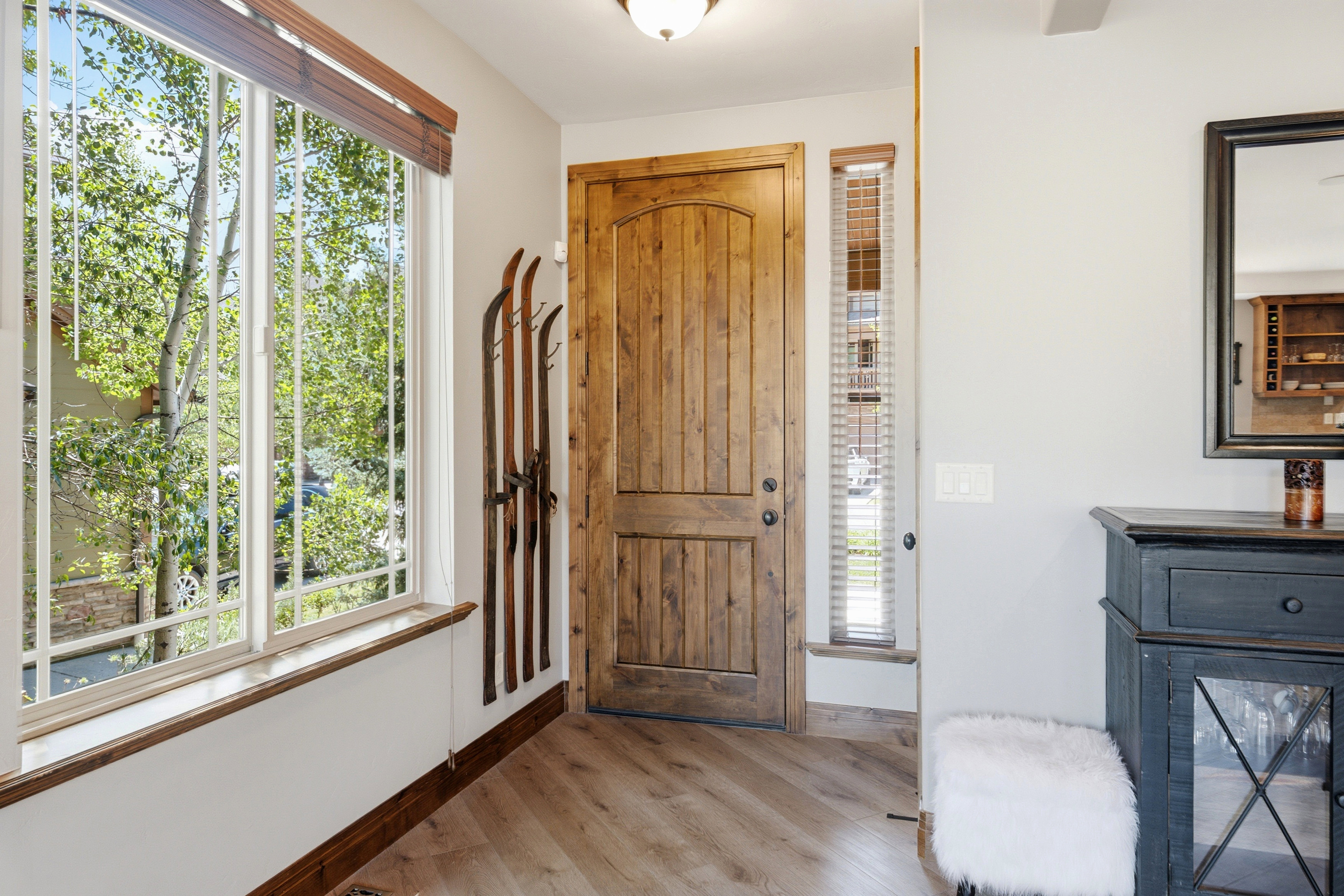 Entryway featuring a solid wood door, large window with wood-finish blinds, wood-finish flooring, and a mirrored accent piece
