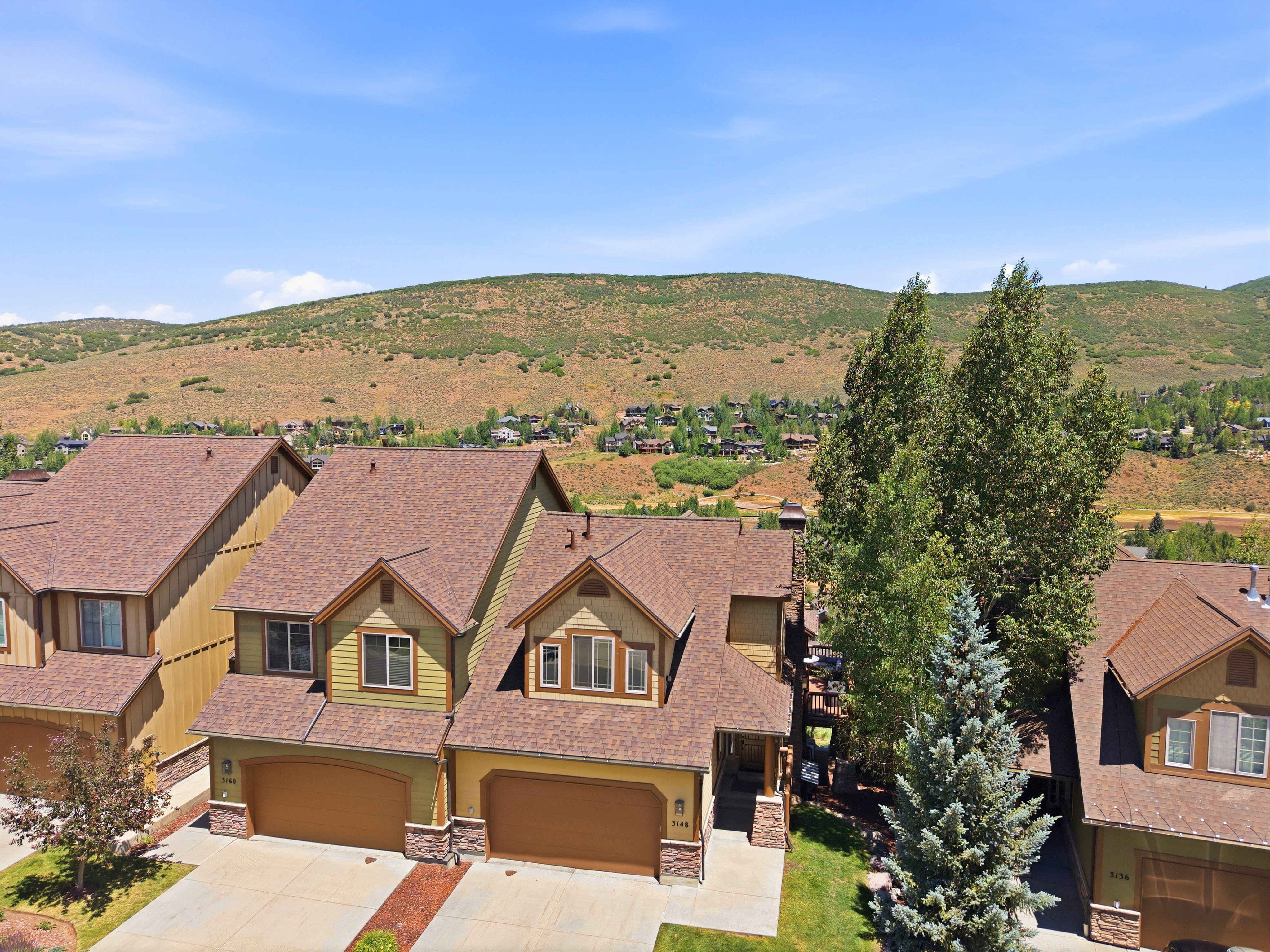 Duplex property featuring multi-toned siding, stone accents, and an attached two-car garage