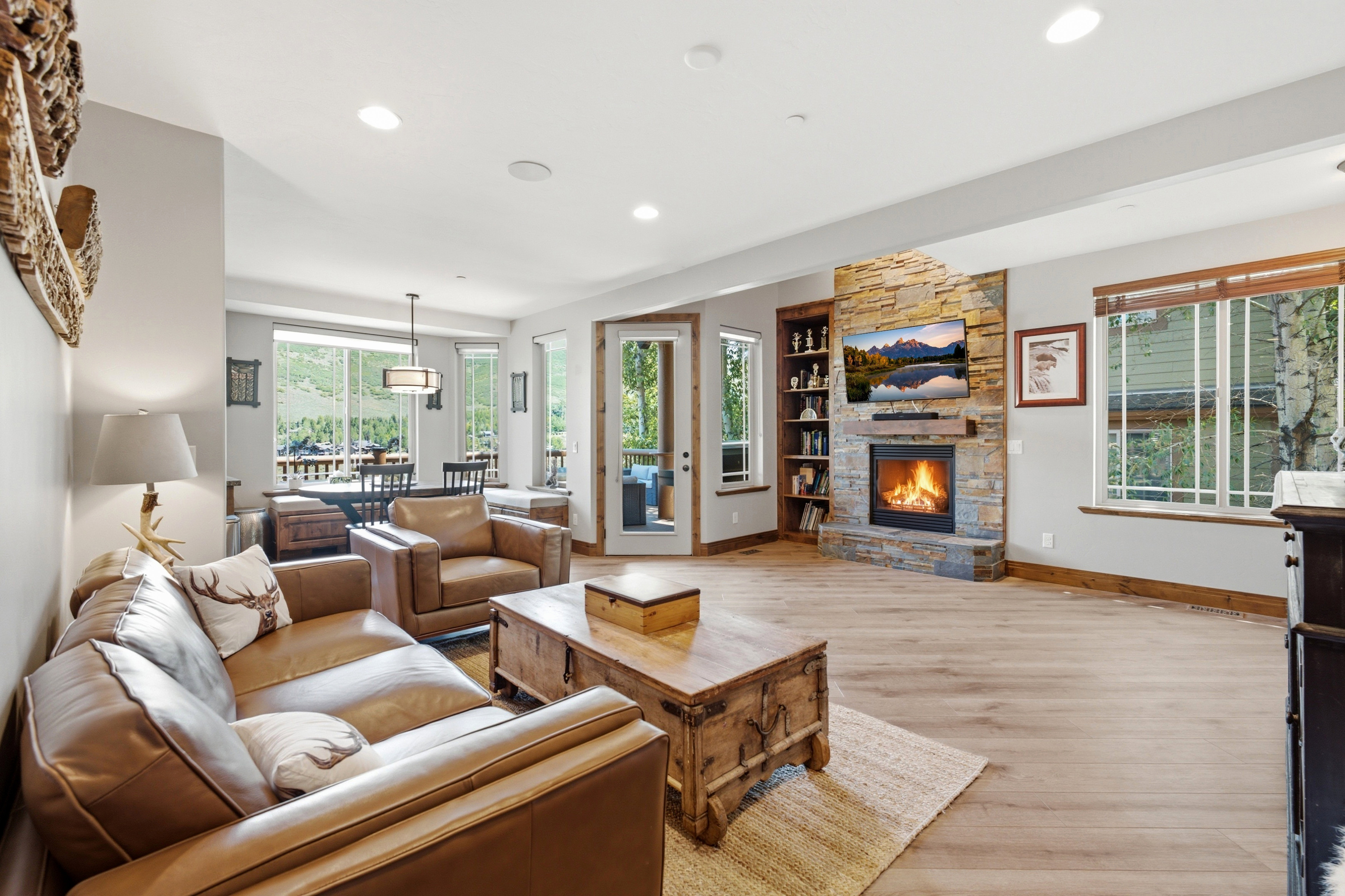 Living area with a stone fireplace, integrated shelving, and wood-finish flooring