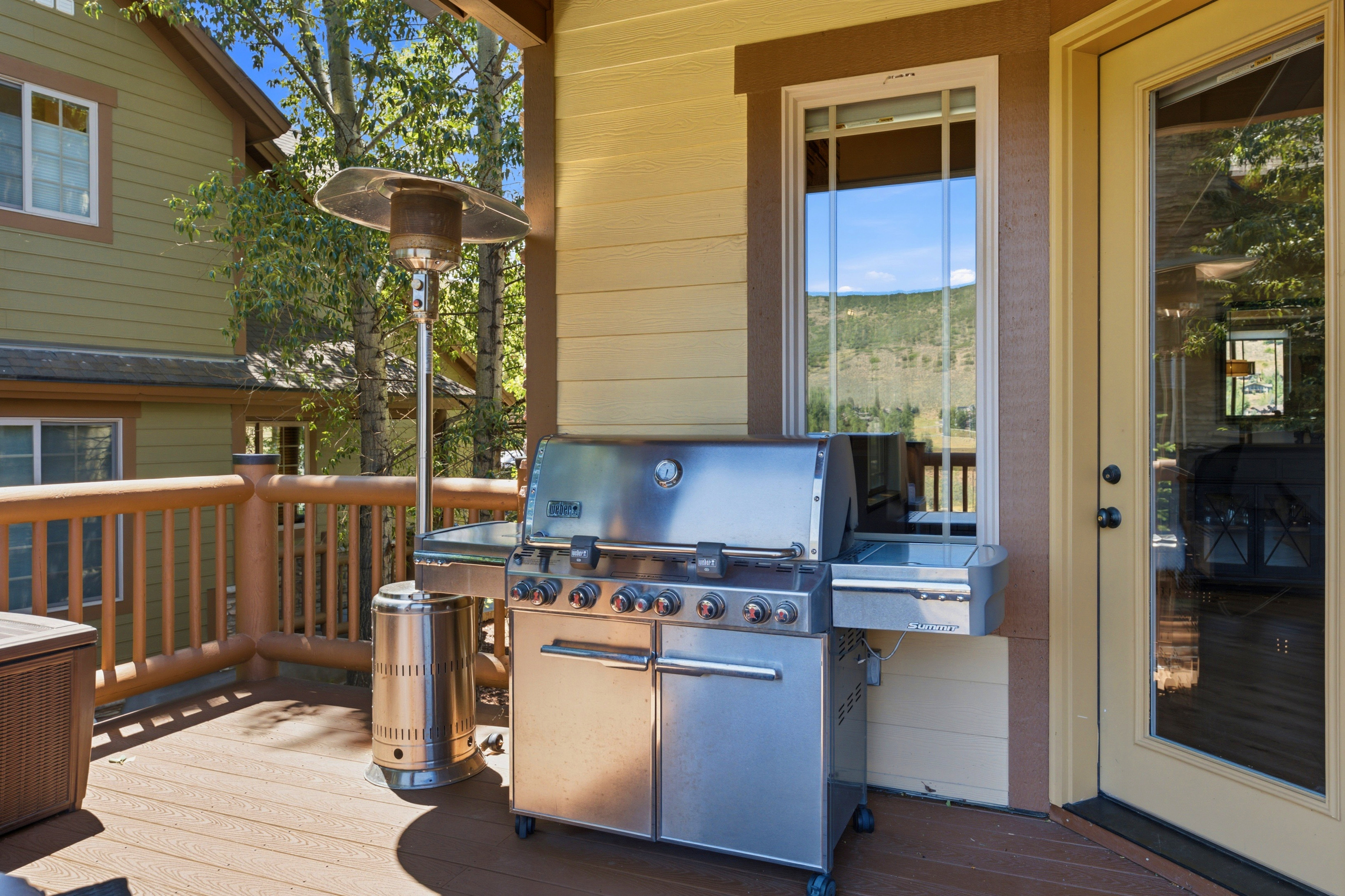 Outdoor deck featuring wood-finish flooring, log-style railings, and a direct entrance via a glass-paneled door