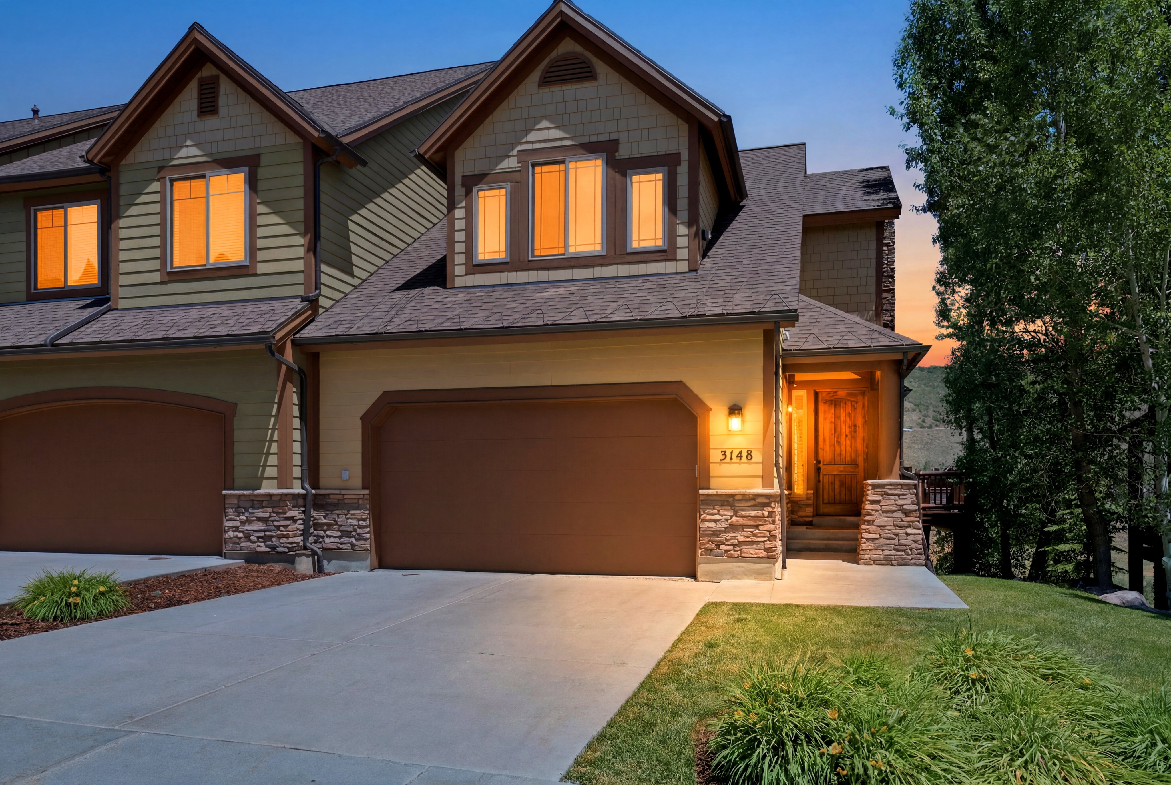 Exterior featuring multi-toned siding, a prominent two-car garage, and stone accents