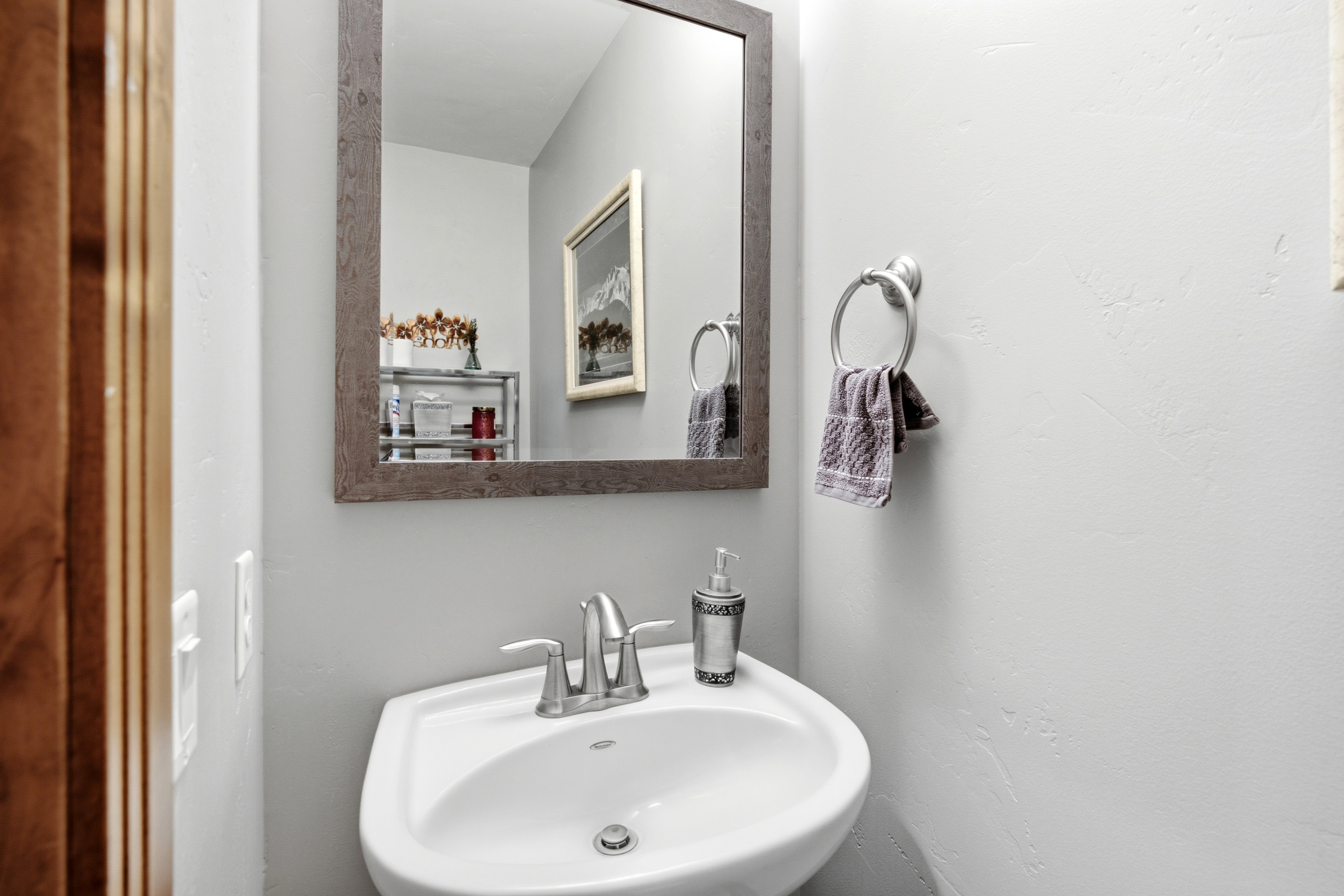 Pedestal sink with a chrome two-handle faucet, set against light gray walls