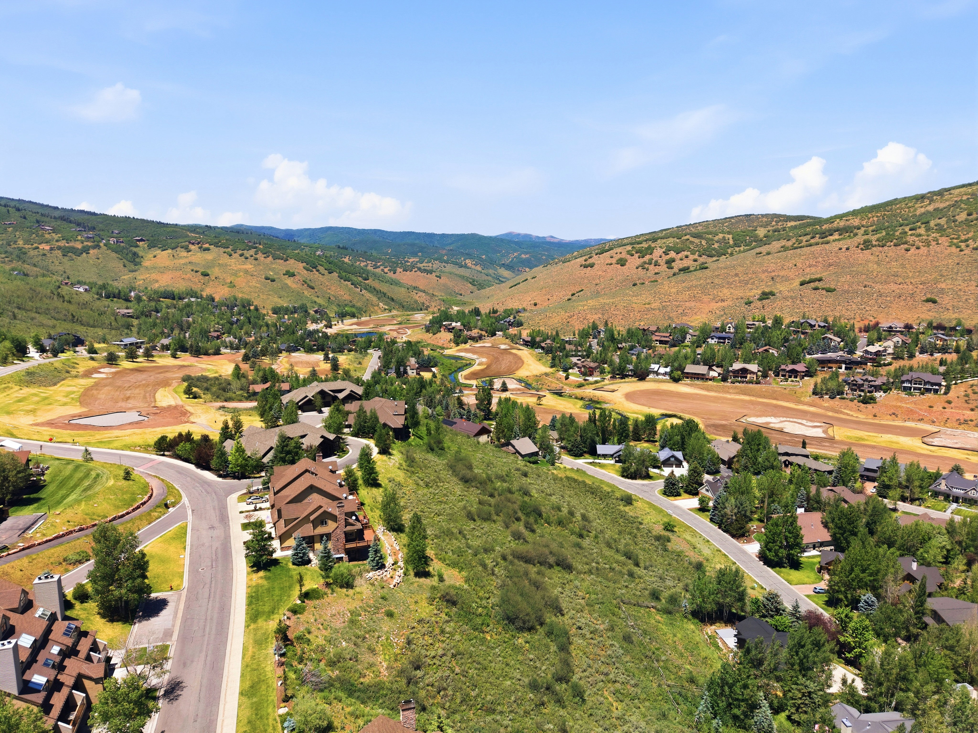 Expansive valley landscape showcasing a residential community with winding roads and numerous trees