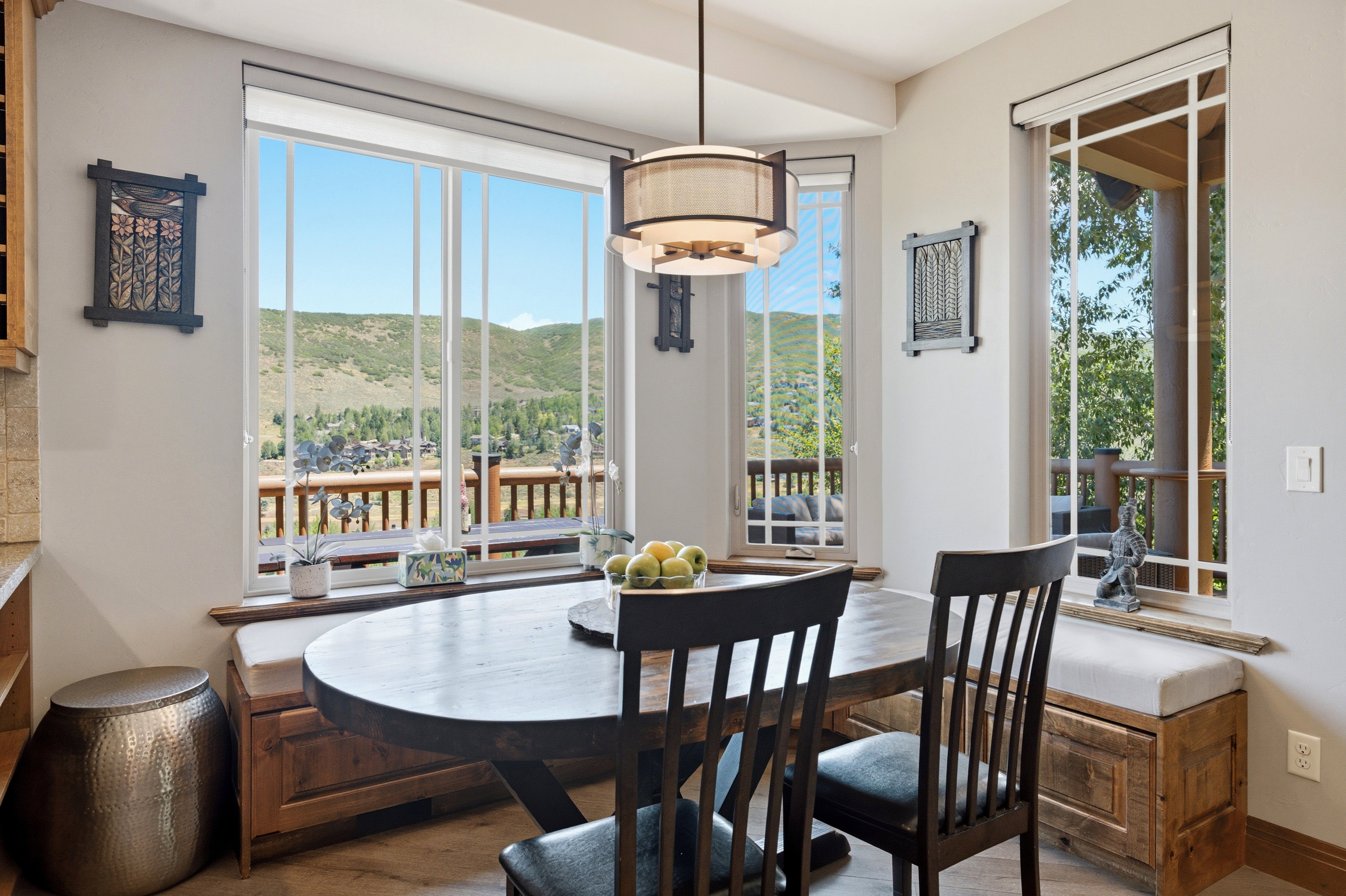 Breakfast nook featuring an oval wood-finish table with two chairs, built-in bench seating with upholstered cushions, and a multi-pane window array