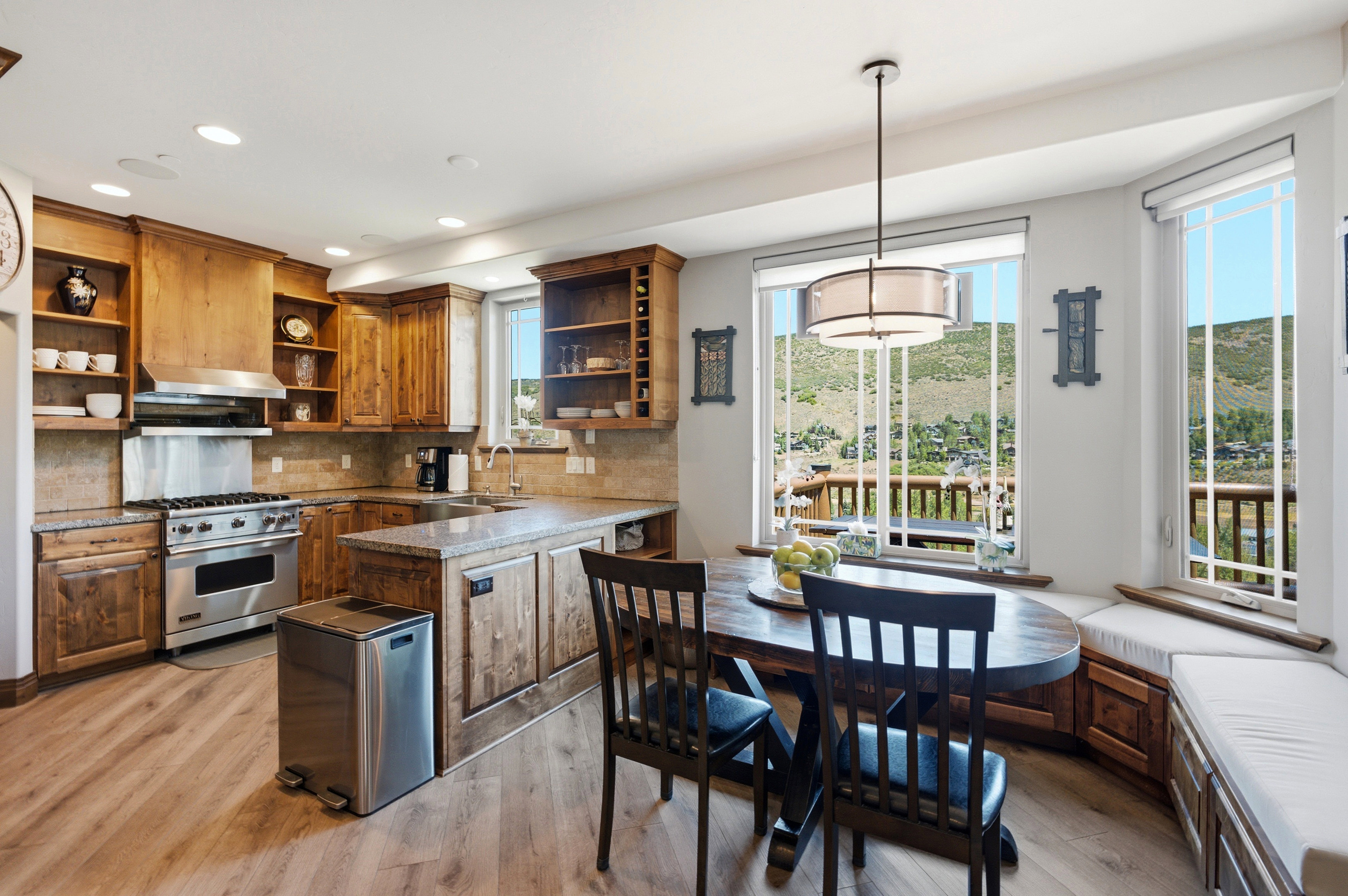Kitchen with wood-finish flooring, custom wood cabinetry, and stone countertops