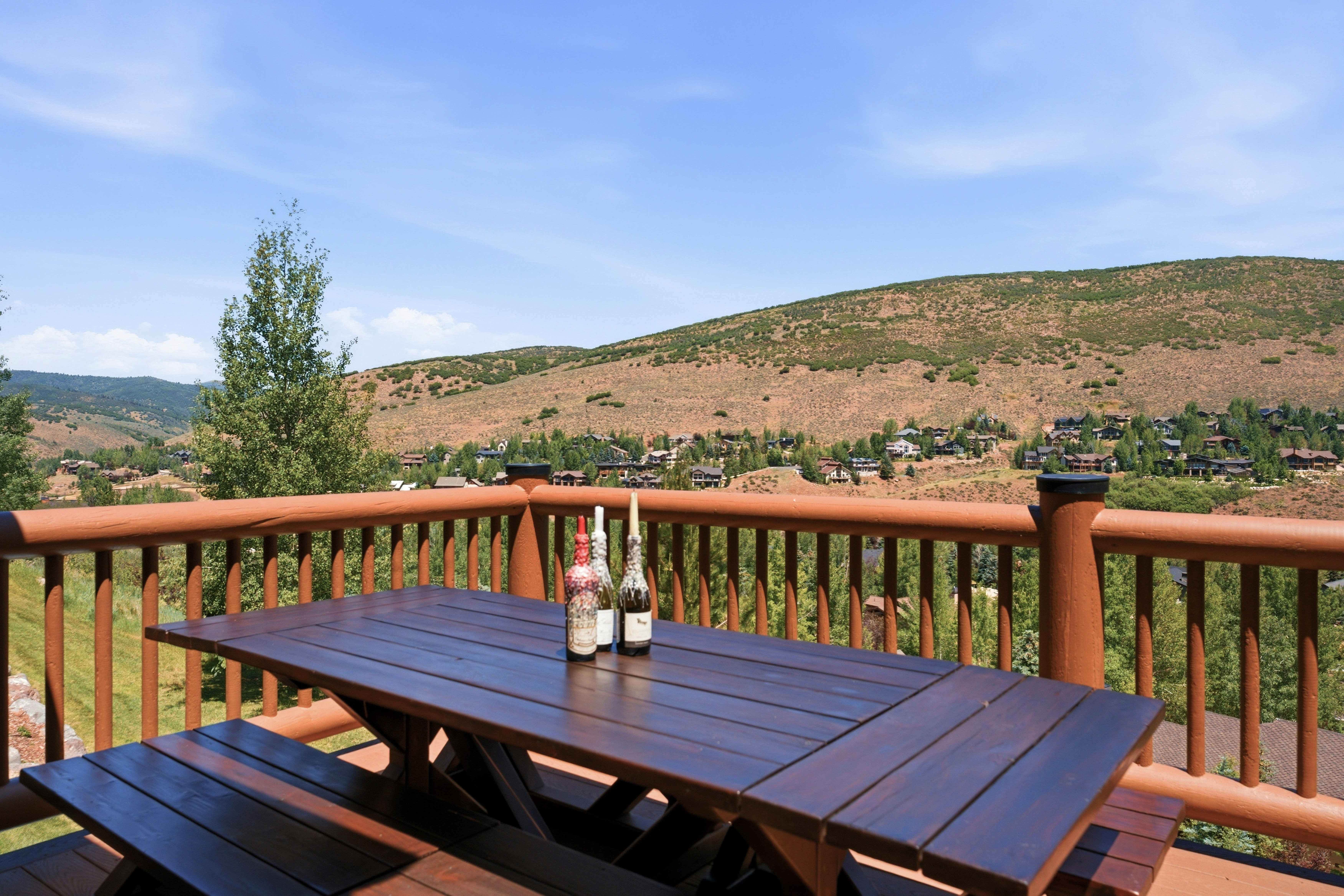Expansive outdoor deck featuring a wooden picnic table and bench seating, surrounded by a robust wooden railing