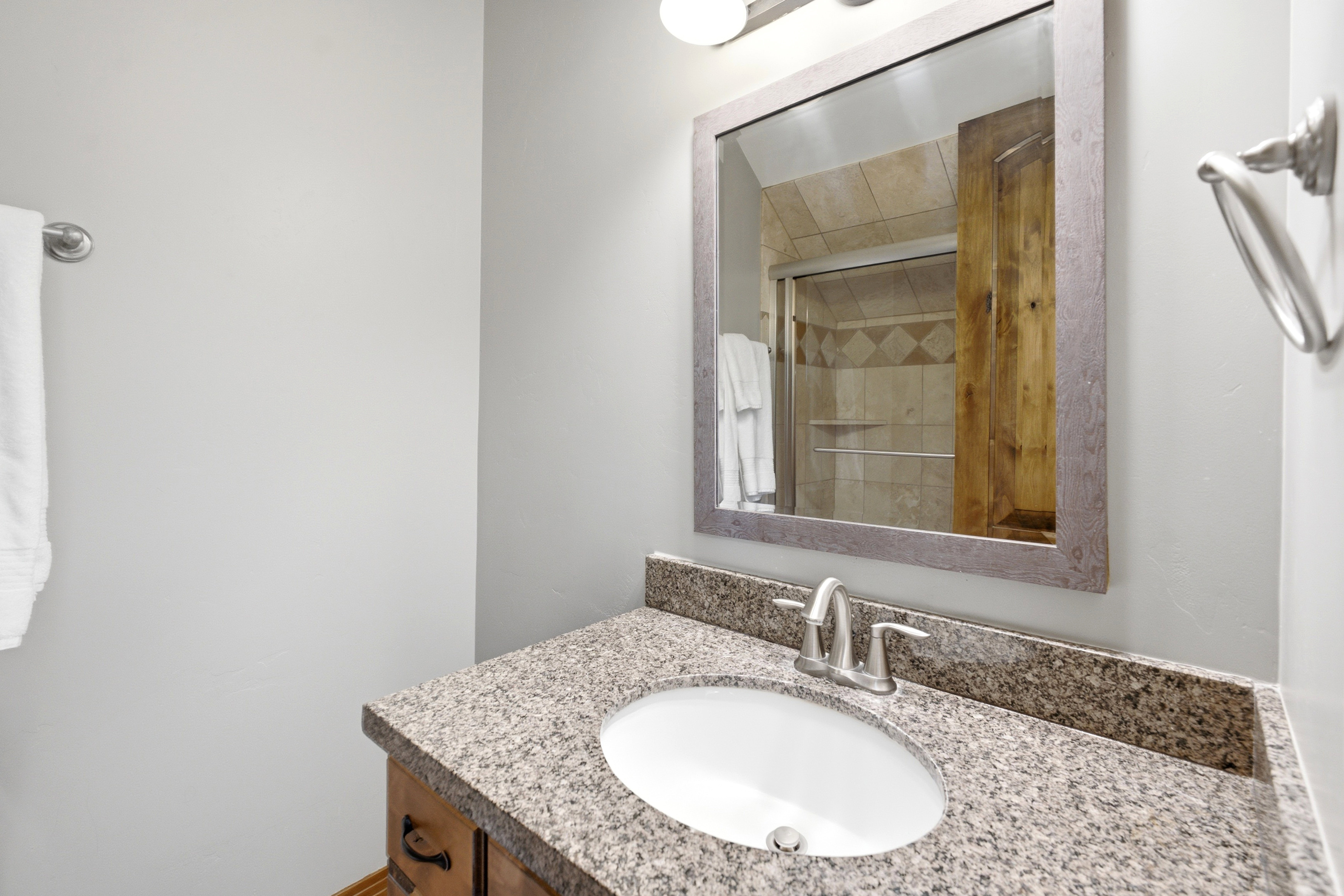 Bathroom vanity with a granite countertop, undermount sink, and brushed nickel faucet