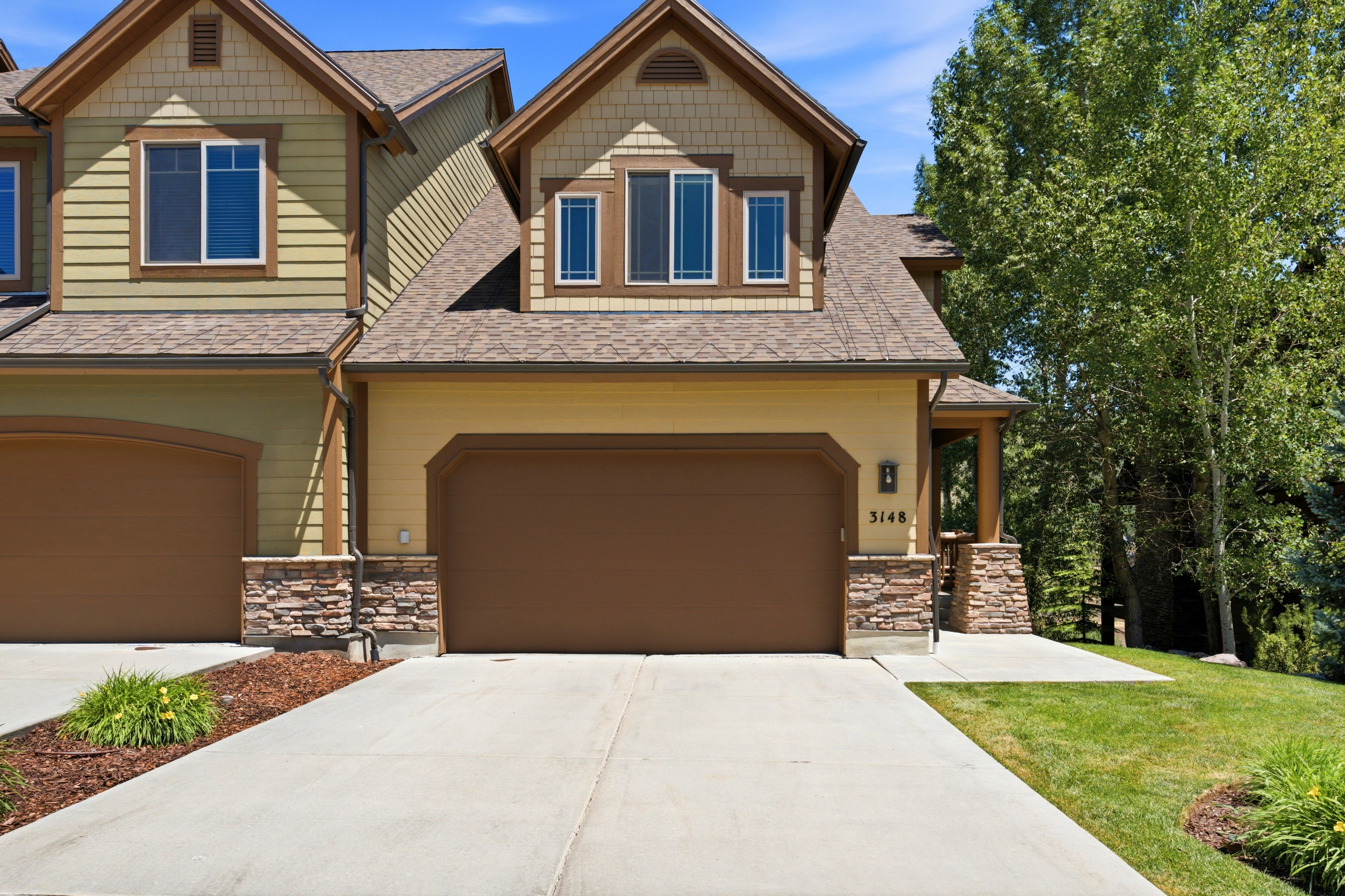 Exterior features include a two-car garage, stone facade accents, a covered entry, and dormer windows