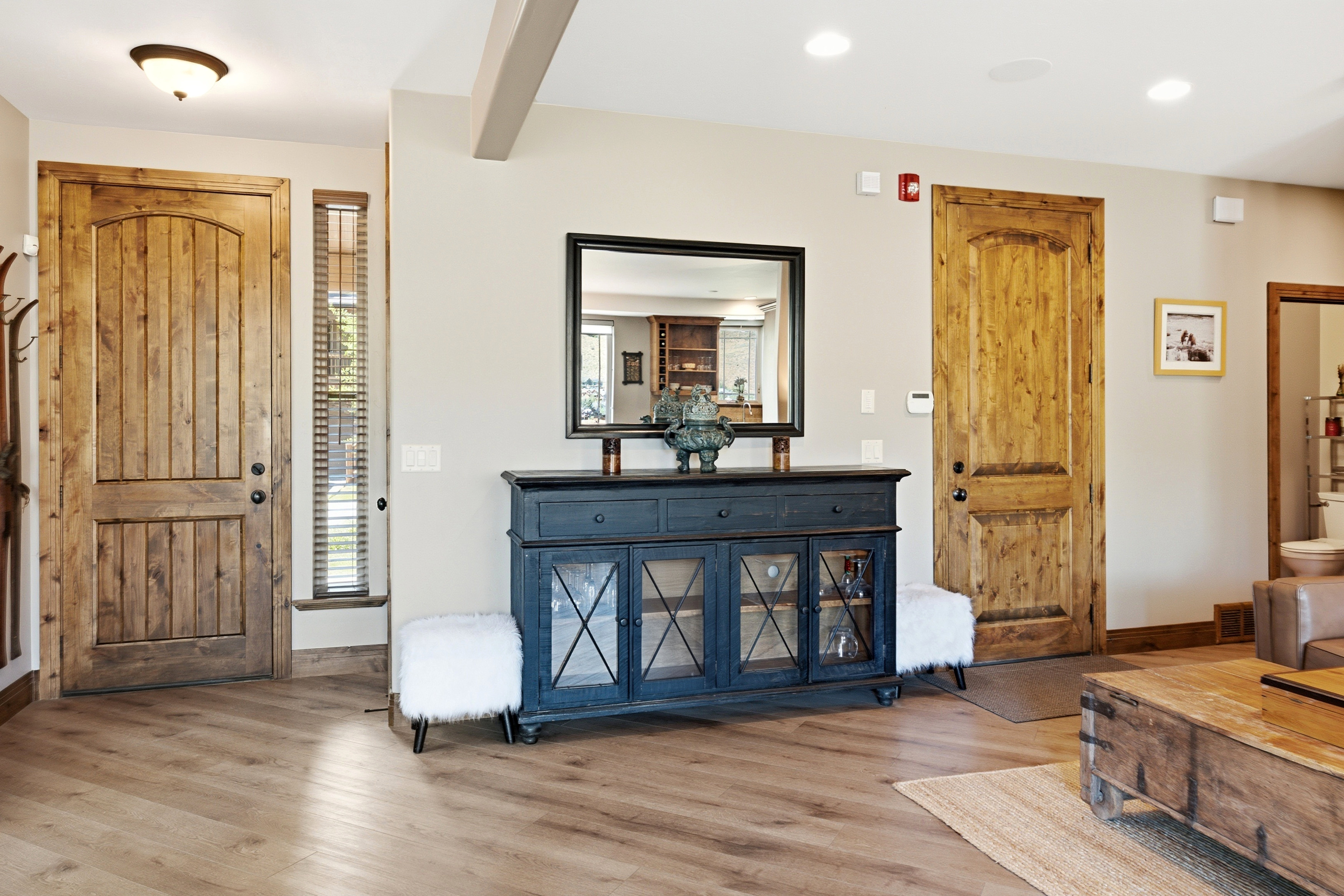 Entryway featuring wood-finish flooring, a wood plank door with an arched top panel, and a vertical window with blinds