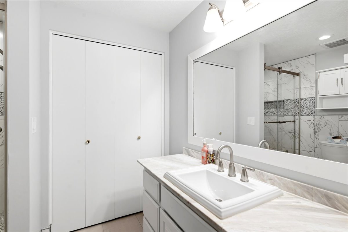 Bathroom vanity featuring a rectangular undermount sink, brushed nickel faucet, and a light-toned countertop