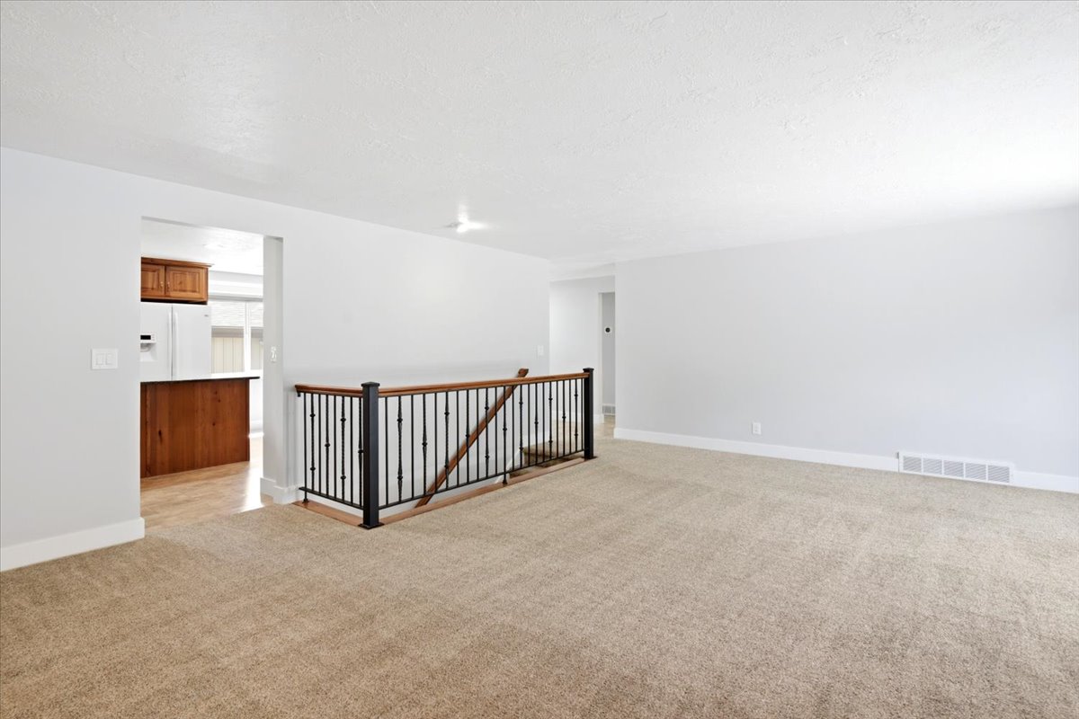 Open-concept living area with neutral carpeting and light-toned walls