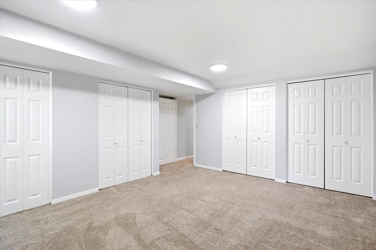 Finished interior space featuring light gray walls, white trim, and neutral carpet flooring