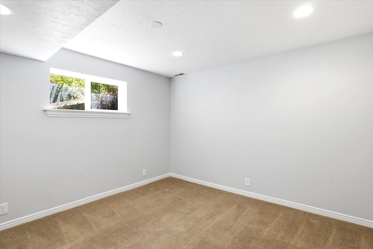 Carpeted room featuring a white-trimmed window, recessed lighting, and light gray walls with white baseboards