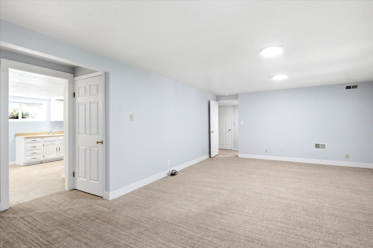 Spacious interior room with light-colored walls and carpeted flooring