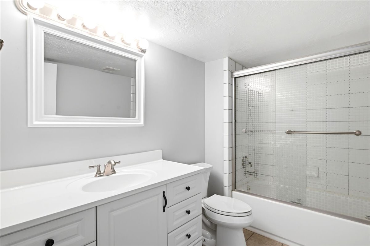 Bathroom featuring a white vanity with integrated sink, brushed nickel faucet, framed mirror, and overhead vanity lighting