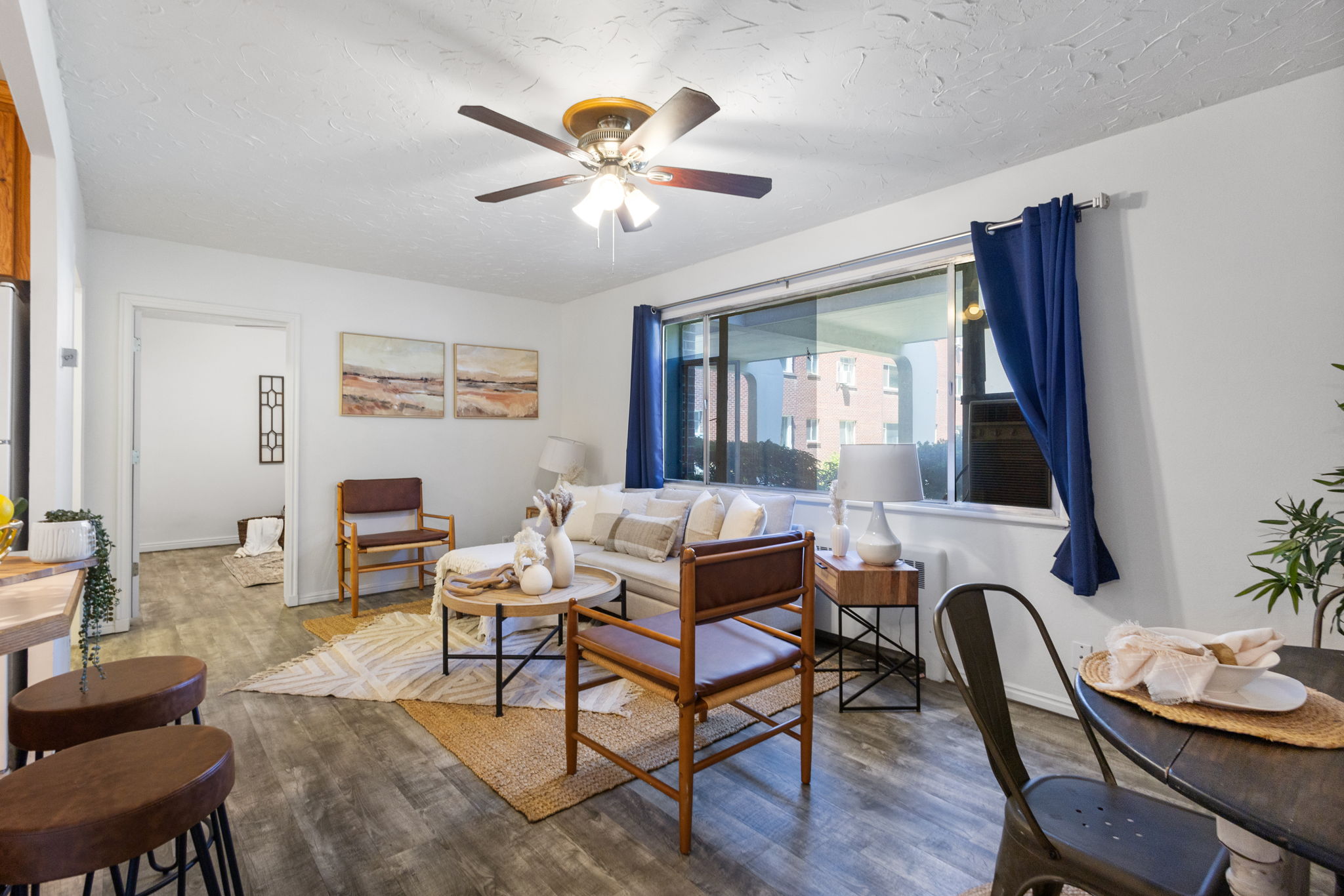 Living area featuring wood-finish flooring, a ceiling fan with integrated lighting, and a large window