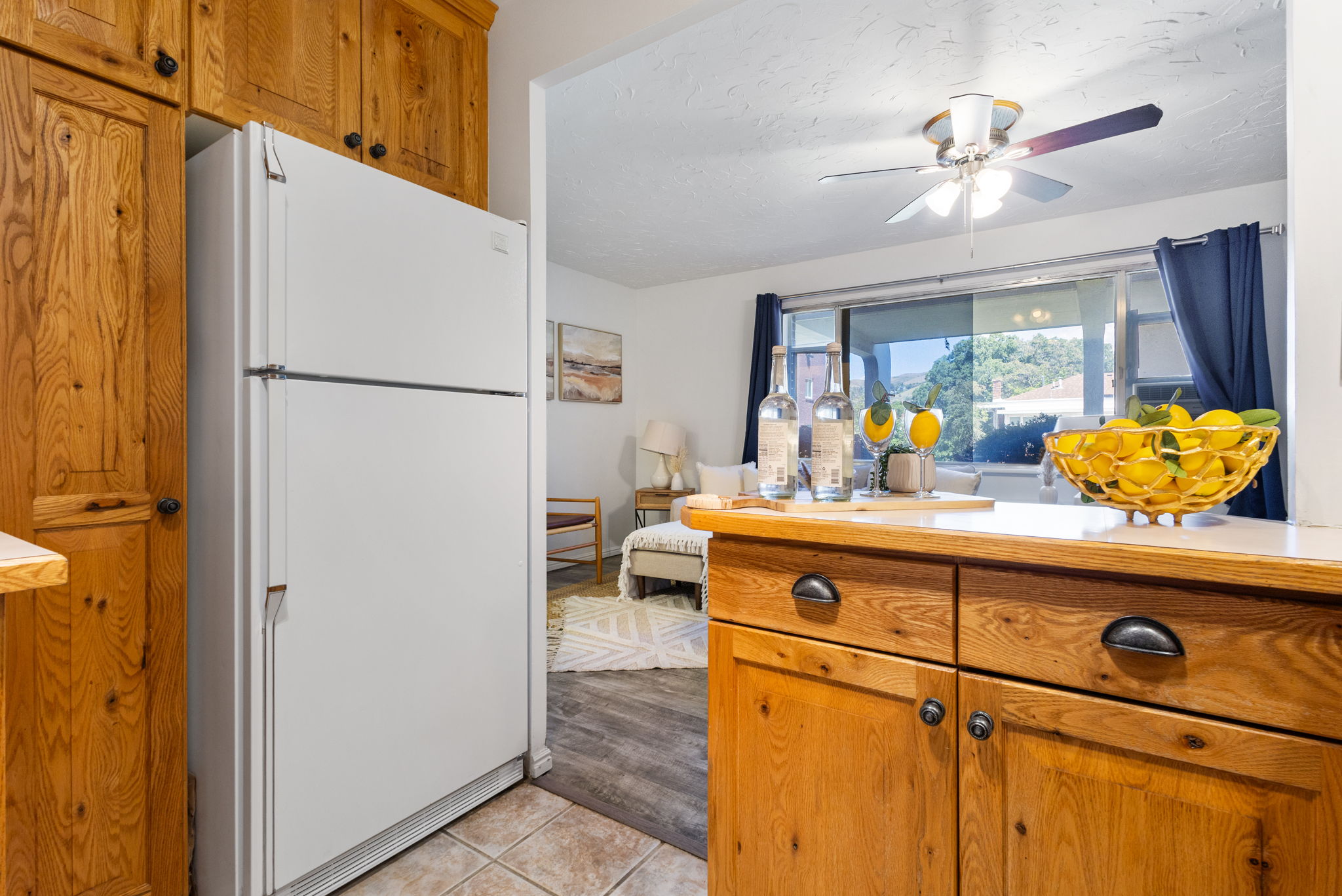 Warm wood cabinetry, integrated white refrigerator, and a breakfast bar with storage drawers and cabinets