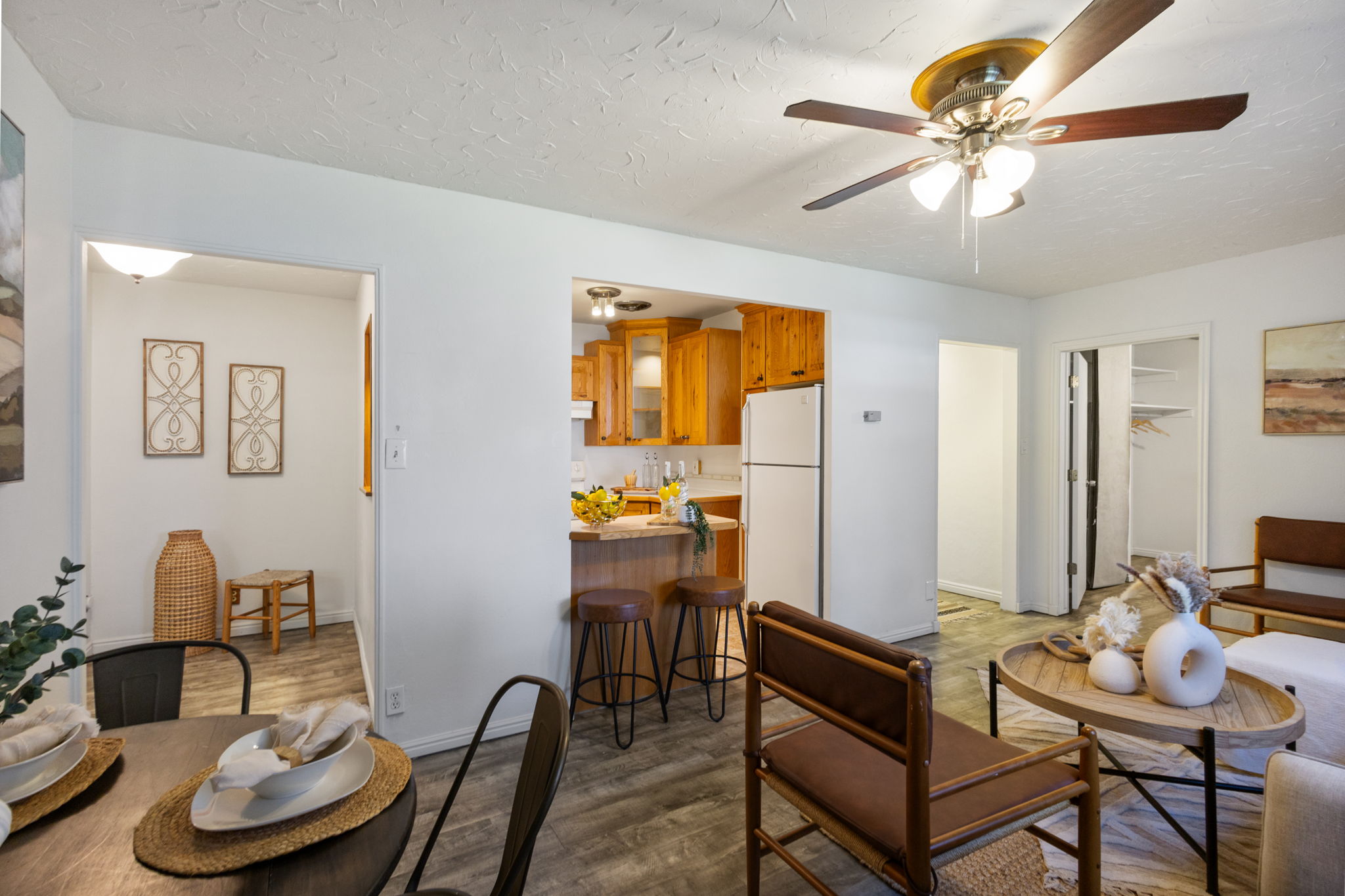 Living area with wood-finish flooring, a ceiling fan, and a kitchen featuring wood cabinetry and white appliances