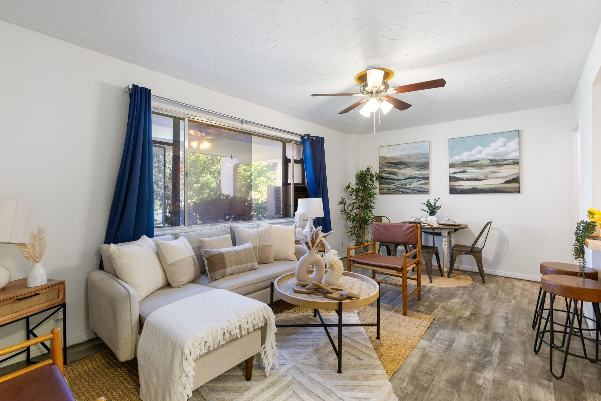 Living area featuring wood-finish flooring, a ceiling fan with integrated lighting and a large window