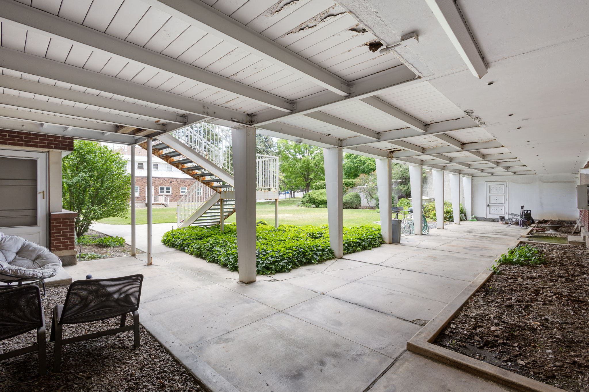 Covered concrete walkway with brick accent walls and an exposed metal staircase