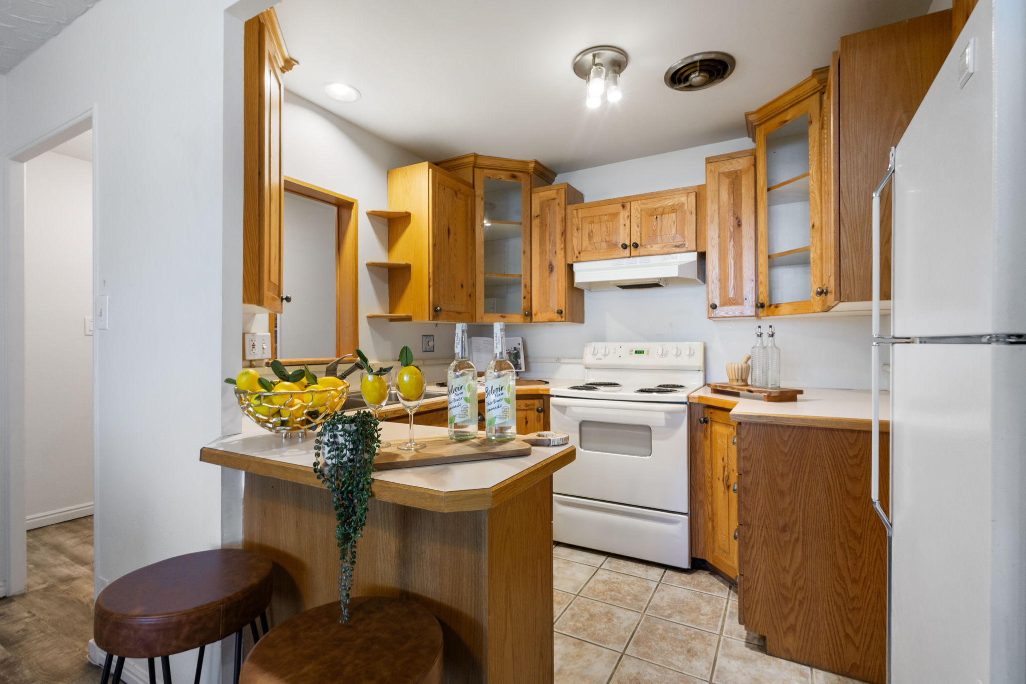 Kitchen featuring wood cabinetry, a built-in breakfast bar, white appliances, and tiled flooring