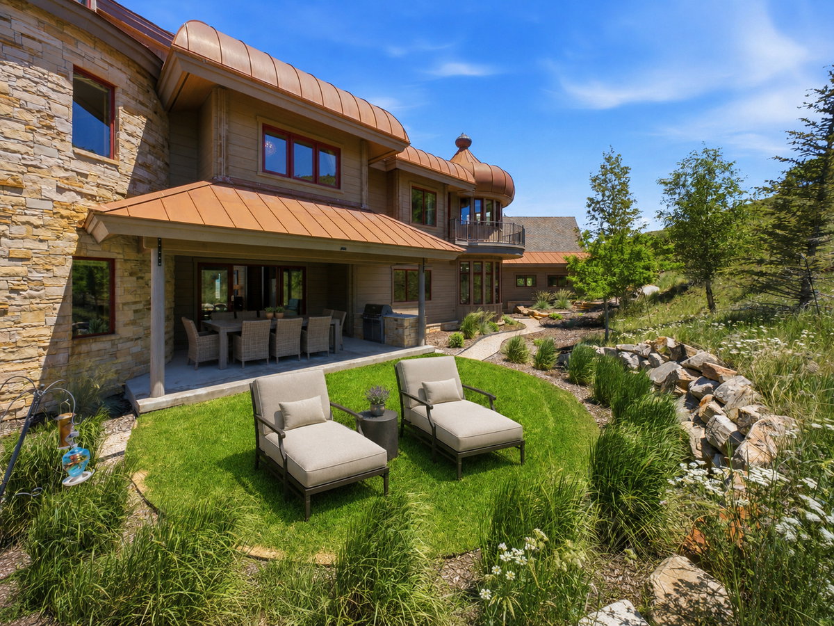 Stone and wood exterior featuring a covered patio, curved copper roofing elements, and an outdoor kitchen area