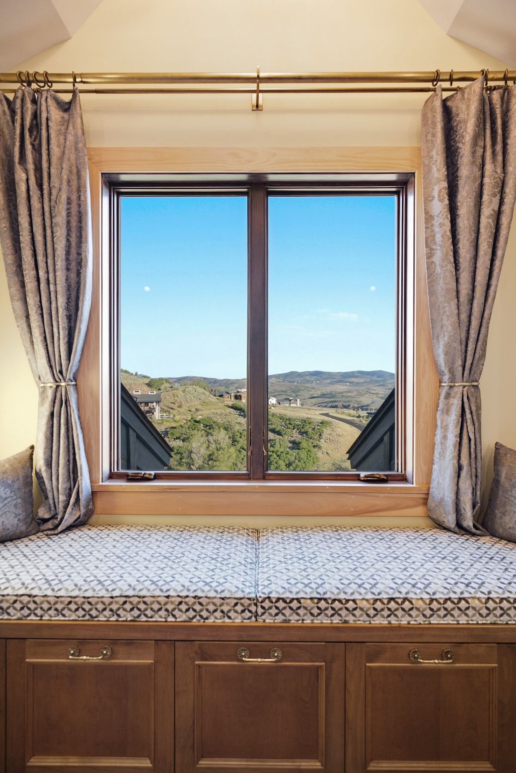 Window seat with built-in cabinetry and upholstered cushions, showcasing a hillside and distant structures