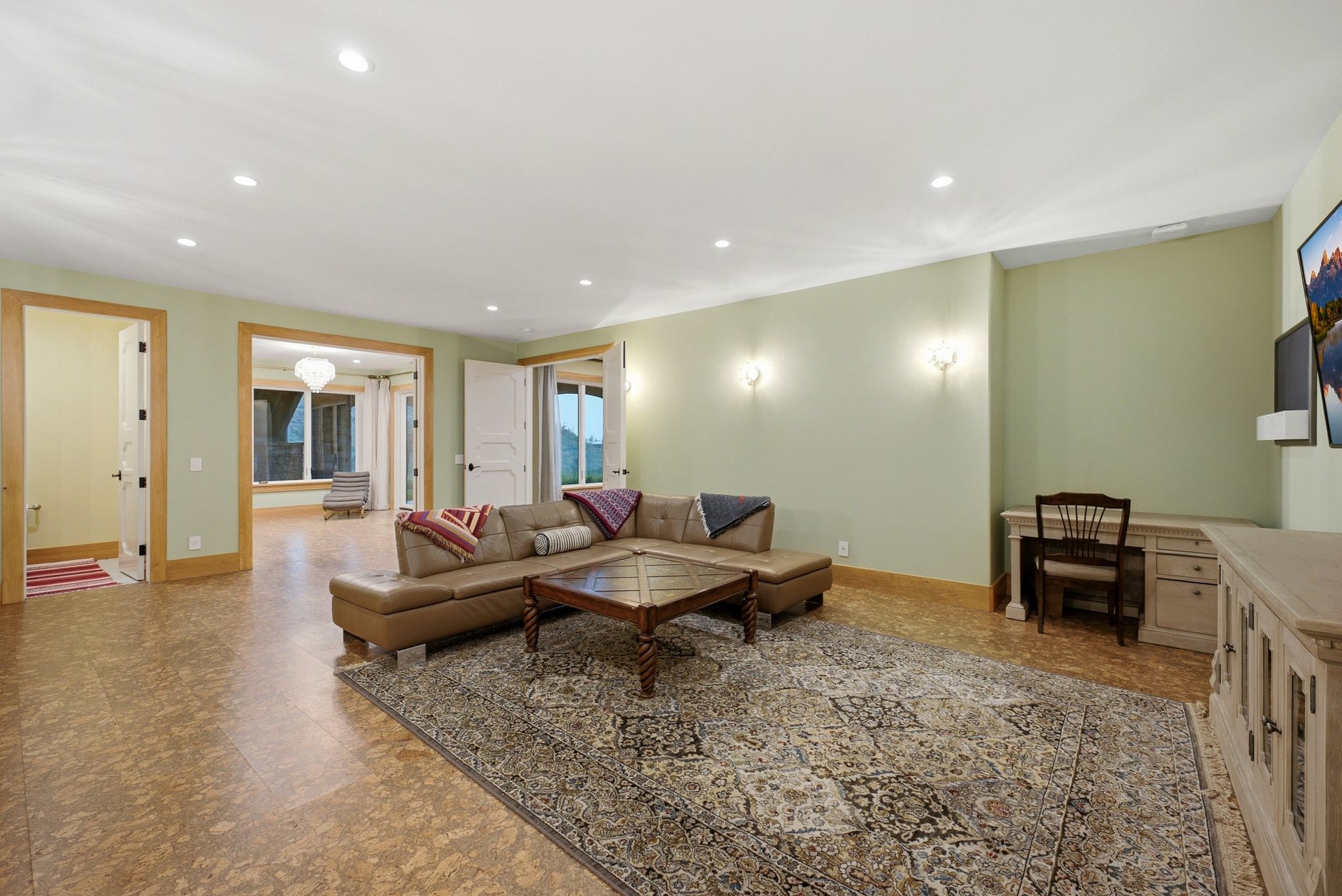 Spacious recreation room featuring recessed lighting, light green walls, wood-finish flooring, and multiple doorways with solid panel doors