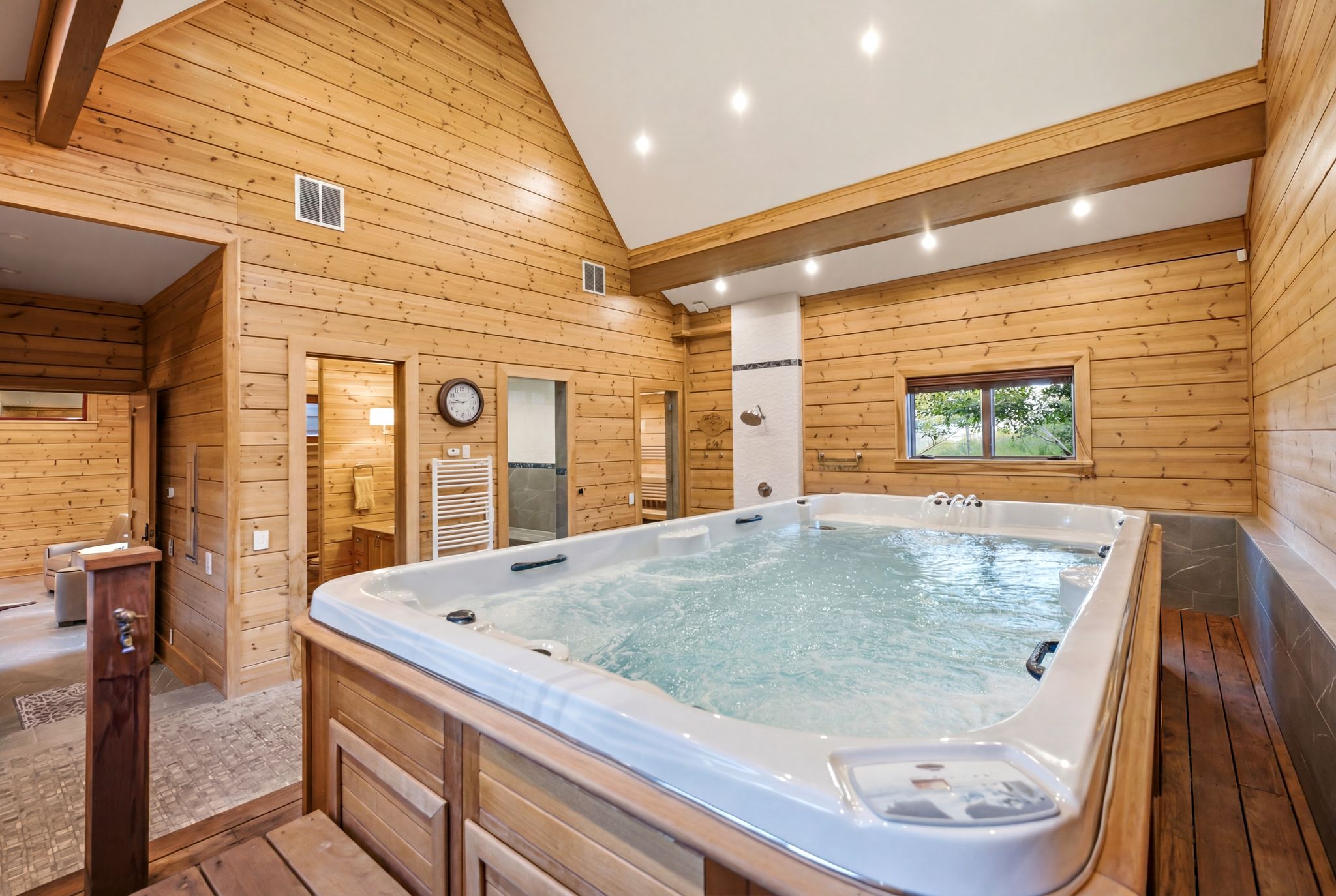 Indoor swim spa with natural wood paneling, vaulted ceilings, and recessed lighting