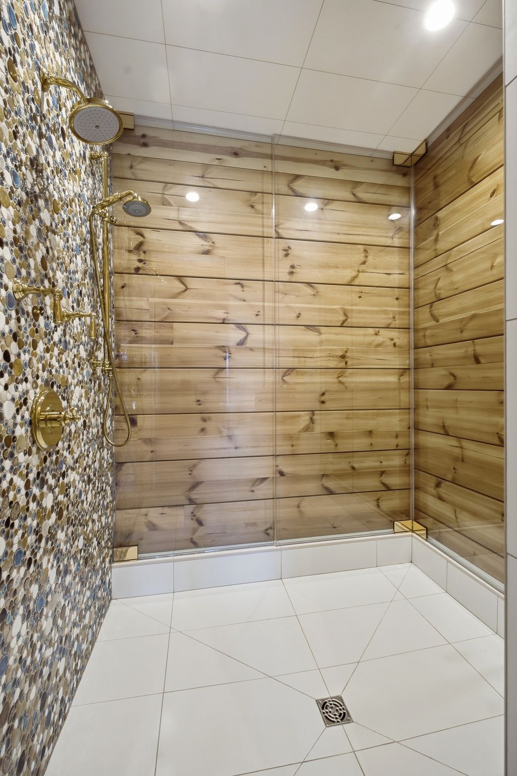 Walk-in shower featuring a glass enclosure, wood-panel wall, mosaic tile wall, and gold-finish fixtures