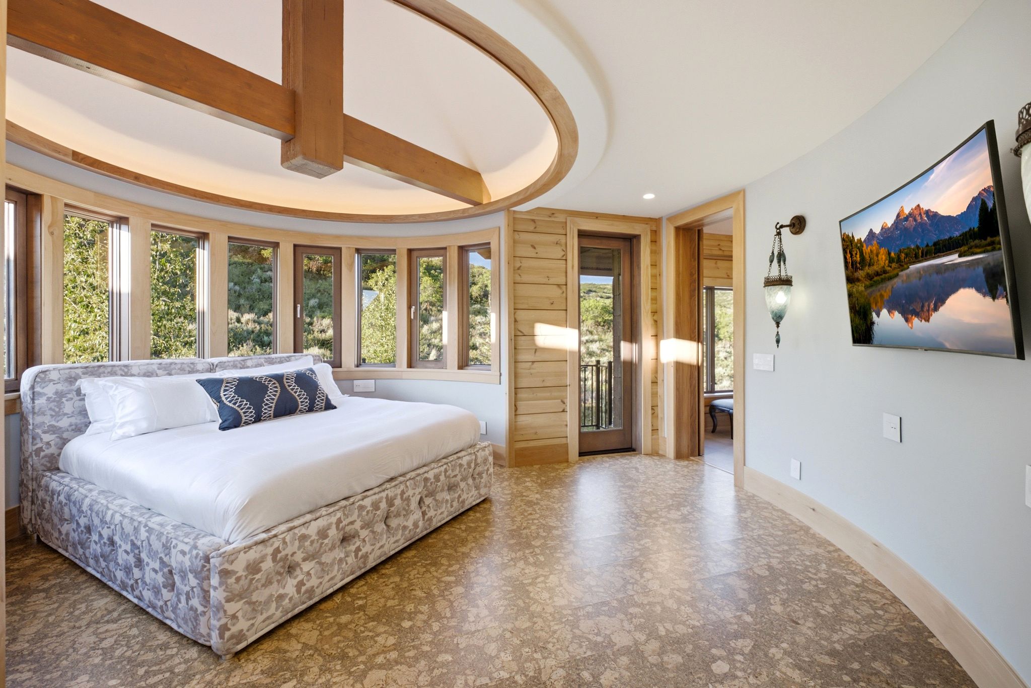 Curved room featuring floor-to-ceiling windows, cork flooring, and a unique circular ceiling design with exposed wood beams