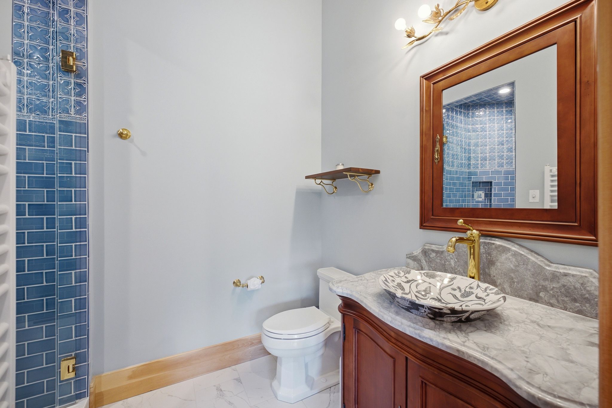 Bathroom featuring a vanity with a patterned vessel sink, gold-tone faucet, and a stone countertop