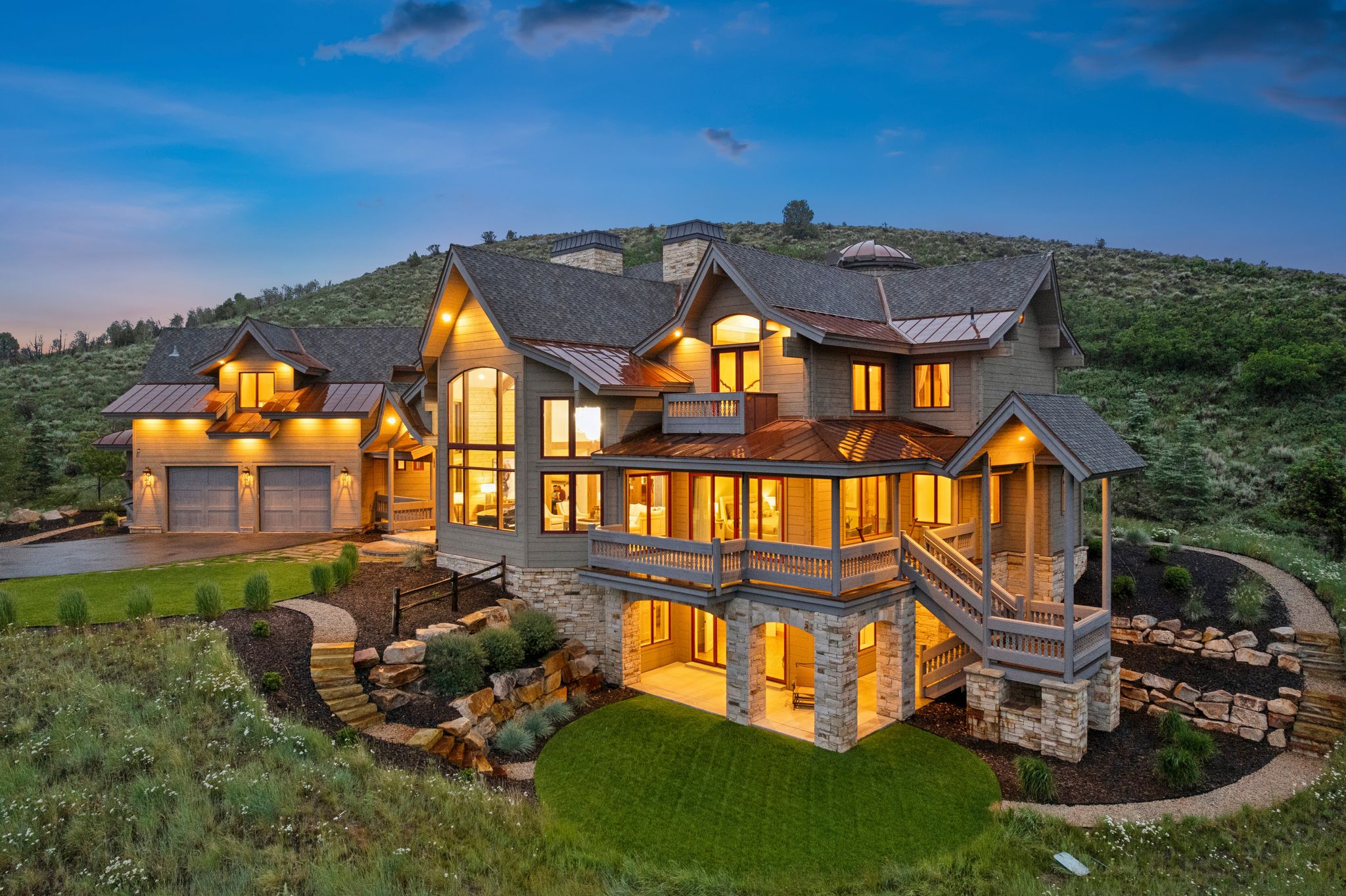 Stone and siding exterior with multiple balconies, a two-car garage, and a walk-out lower level