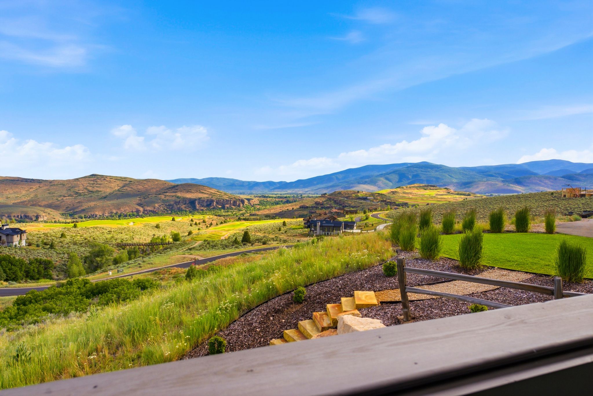 Expansive mountain and valley scenery featuring distant residential structures