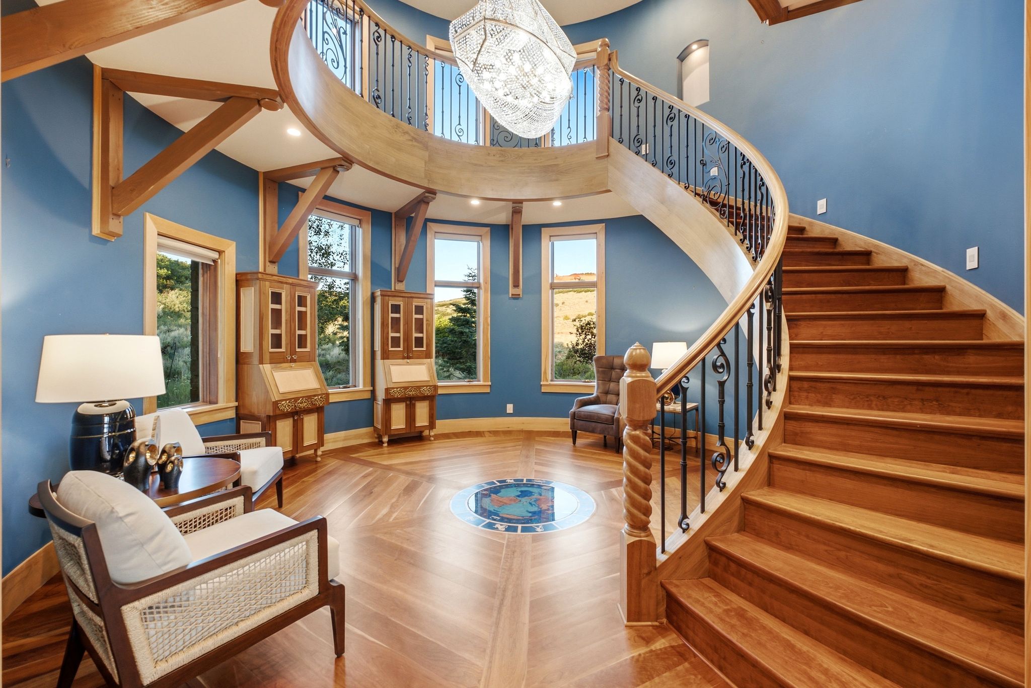 Grand curved staircase with decorative wrought iron balusters and a custom wood newel post