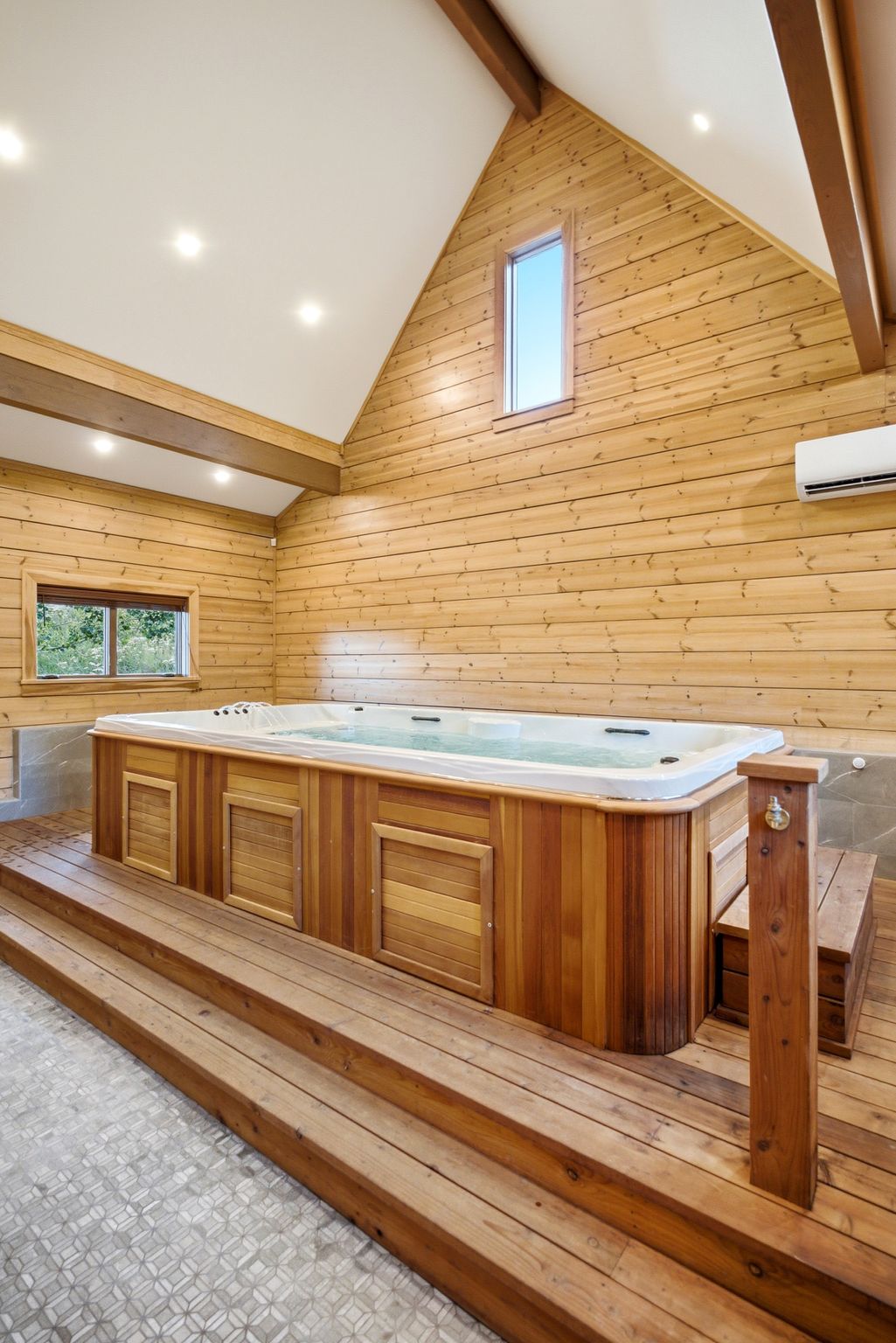 Indoor spa with a wood-finish surround set on a multi-tiered wood-finish deck