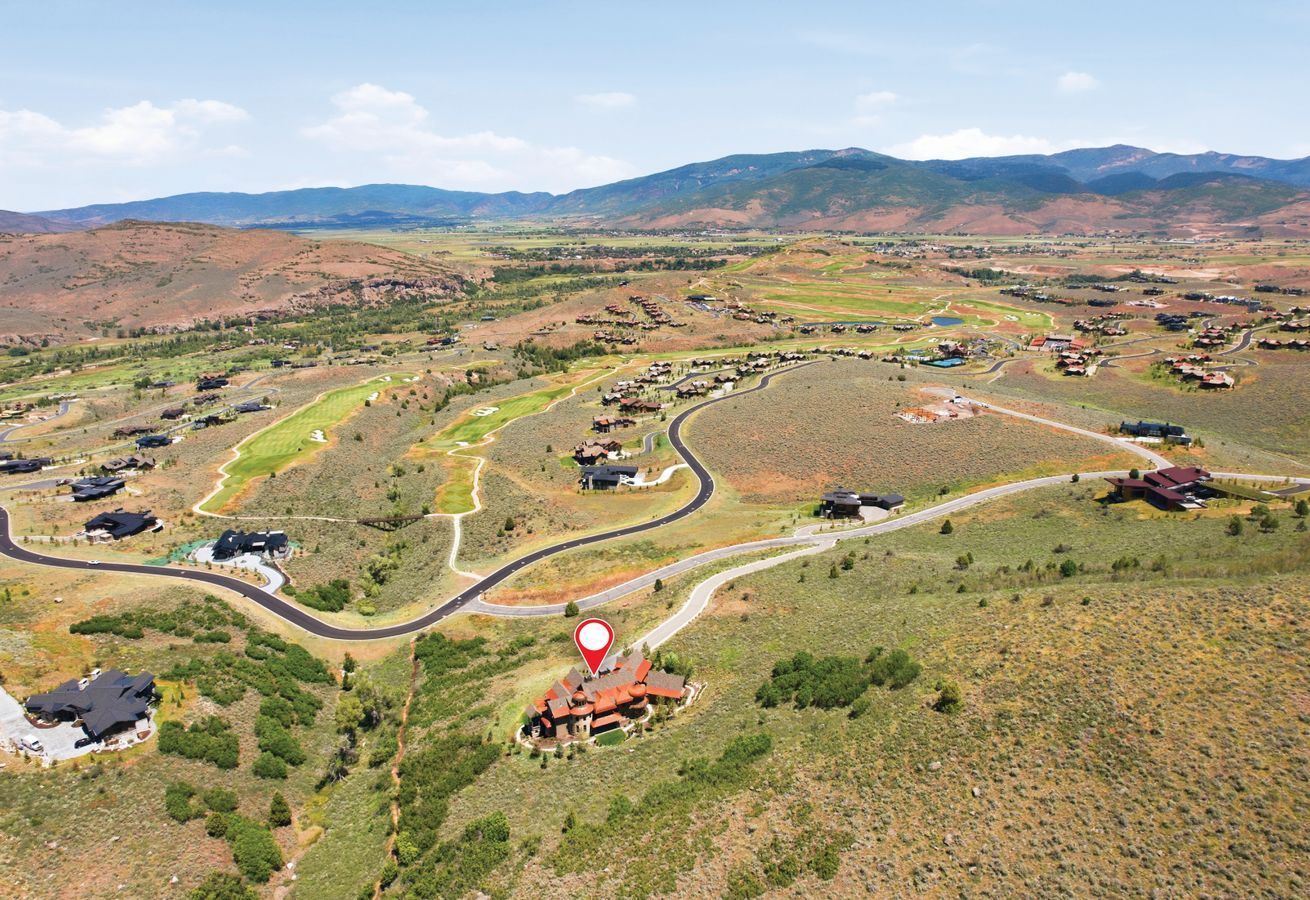 Expansive aerial perspective showcasing a property surrounded by rolling terrain and distant mountains